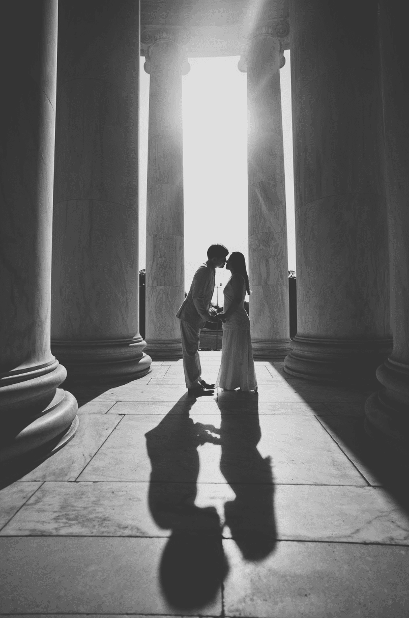 Black and white silhouette of couple kissing between dramatic marble columns at the Jefferson Memorial