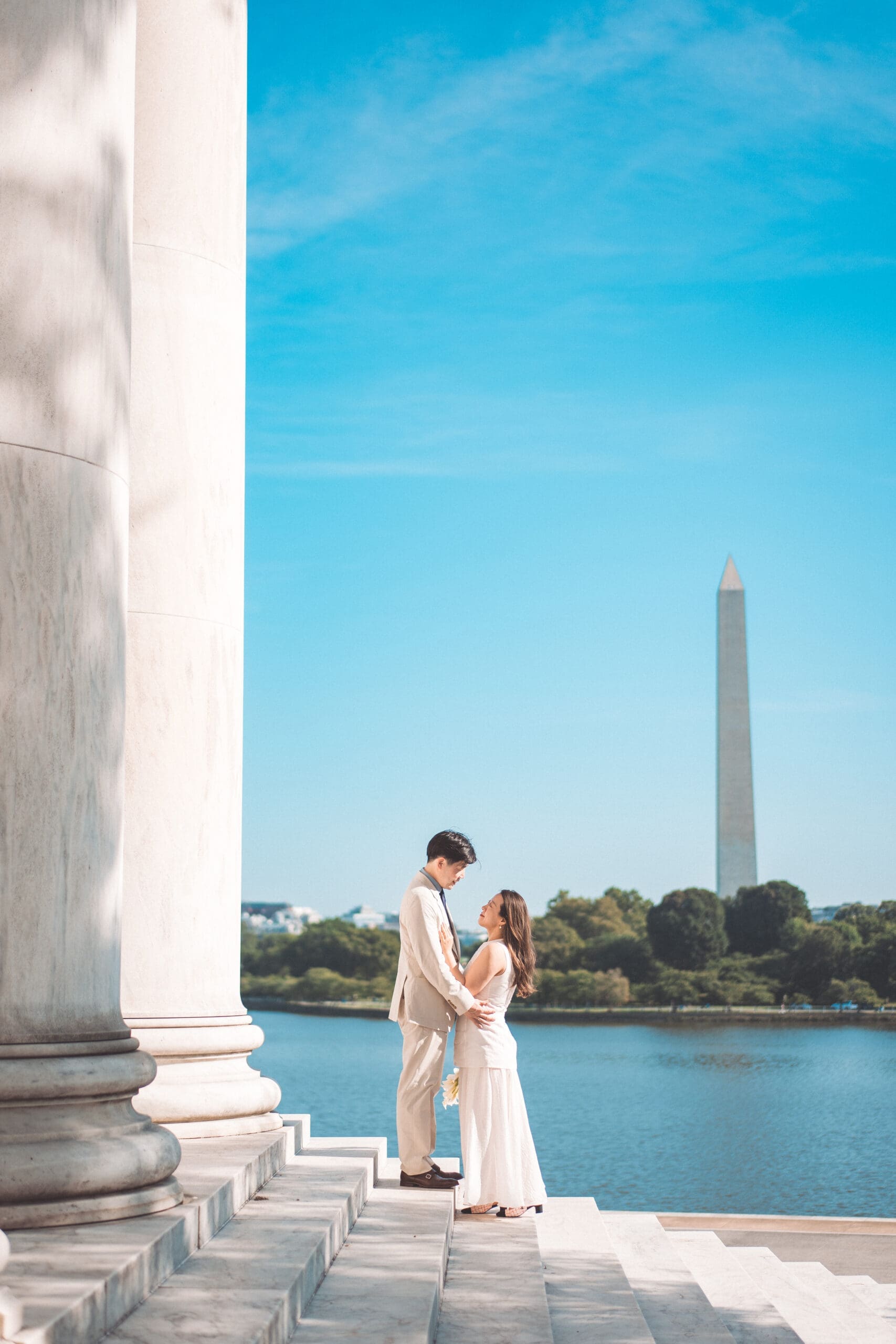 Couple sharing an intimate moment by the water with the Washington Monument in the background during their Washington DC engagement