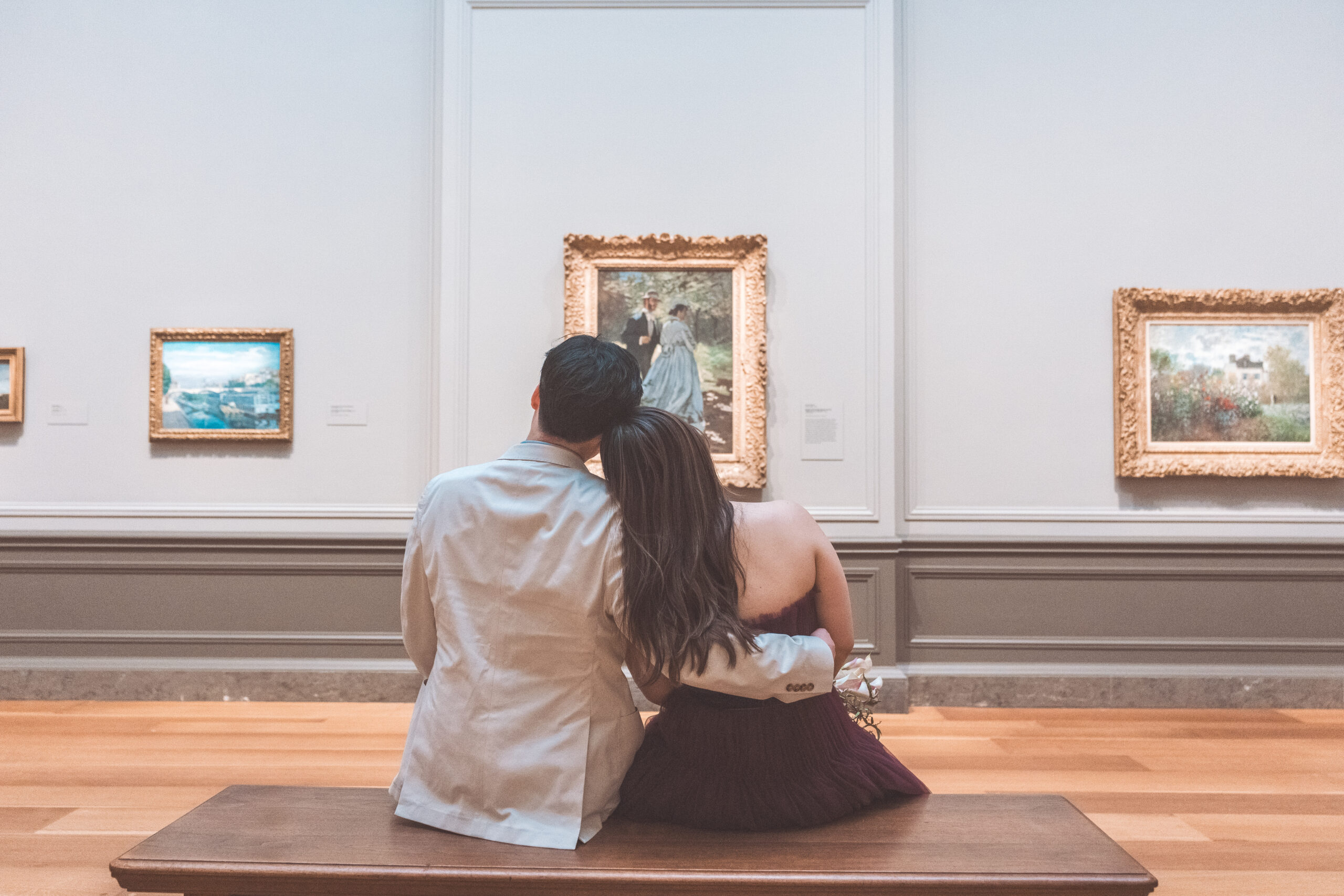 Couple sitting together in a museum gallery admiring framed artwork during an intimate engagement session in Washington DC