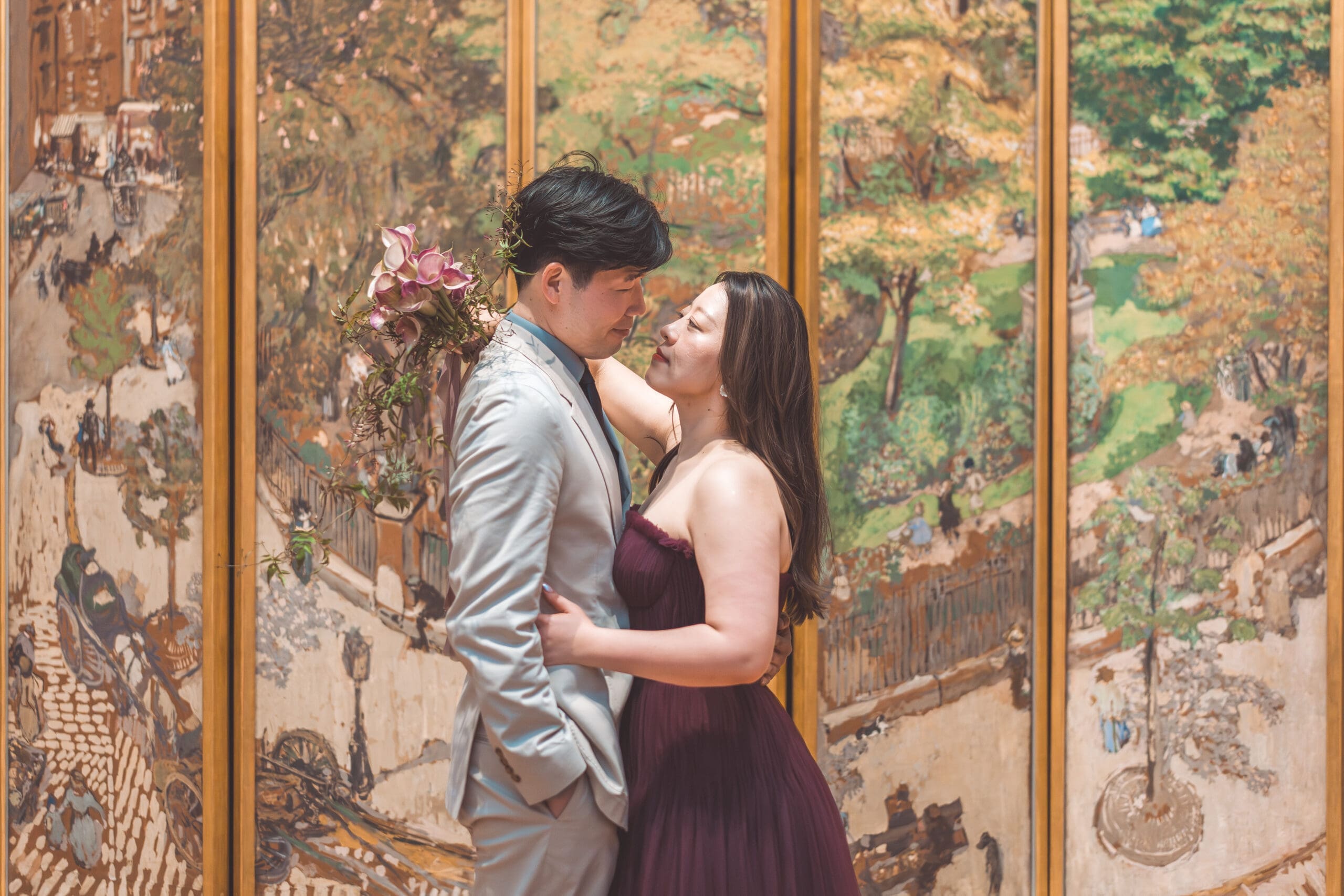 Stylish couple embracing inside an art museum surrounded by painted garden murals and editorial details