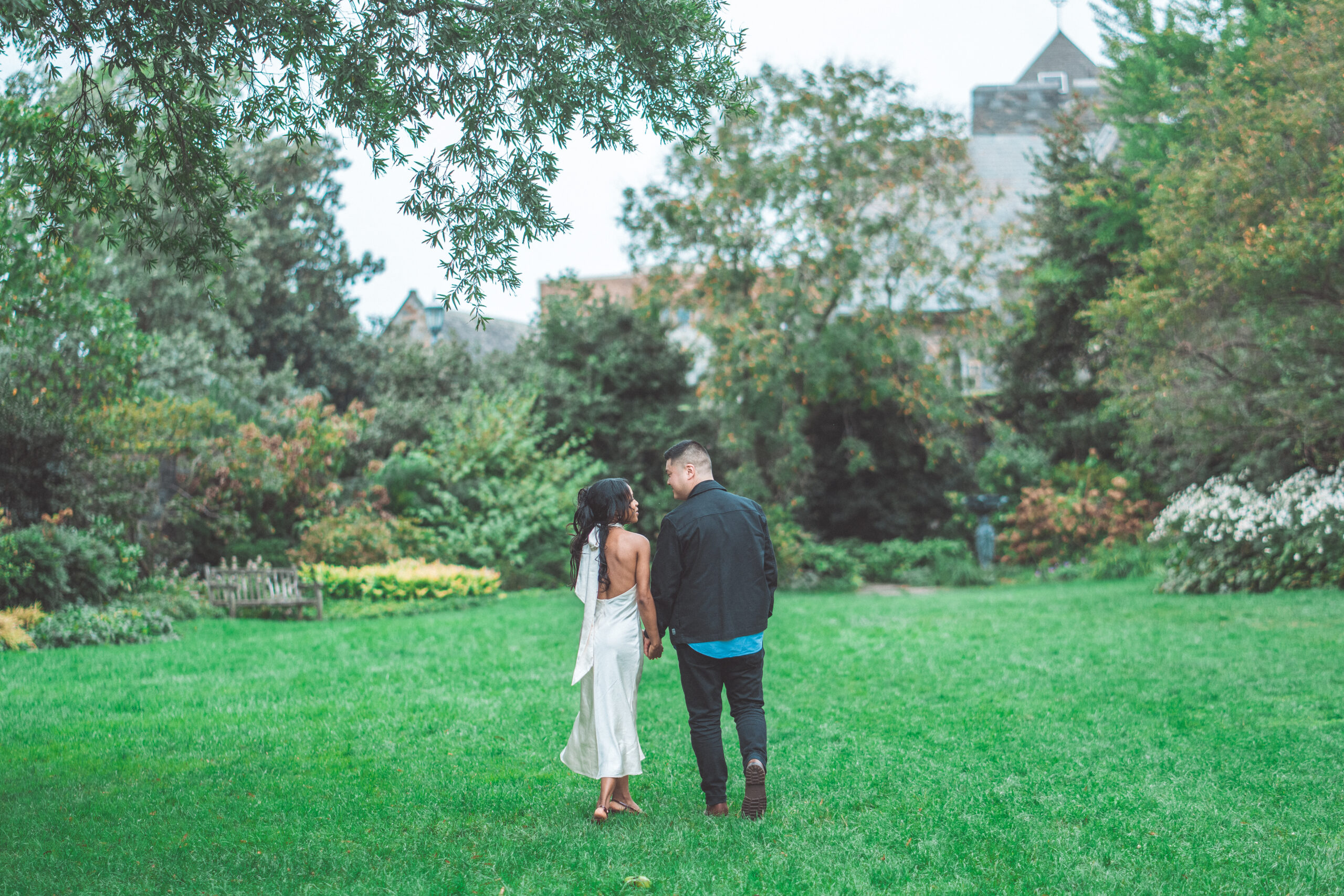 Couple walking hand in hand through a lush formal garden during their intimate engagement session in Washington DC