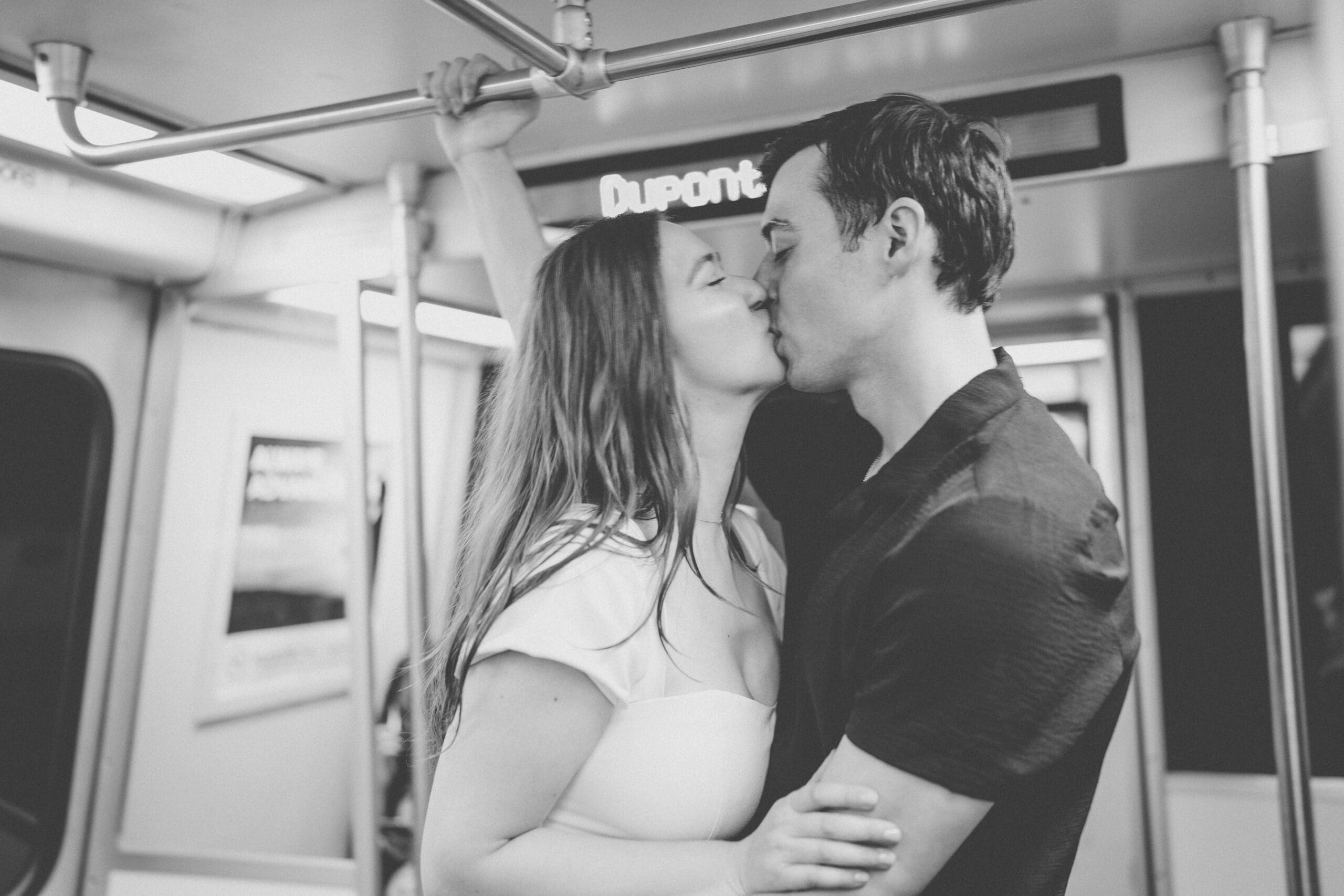 Black and white portrait of a couple kissing inside a Washington Metro train station
