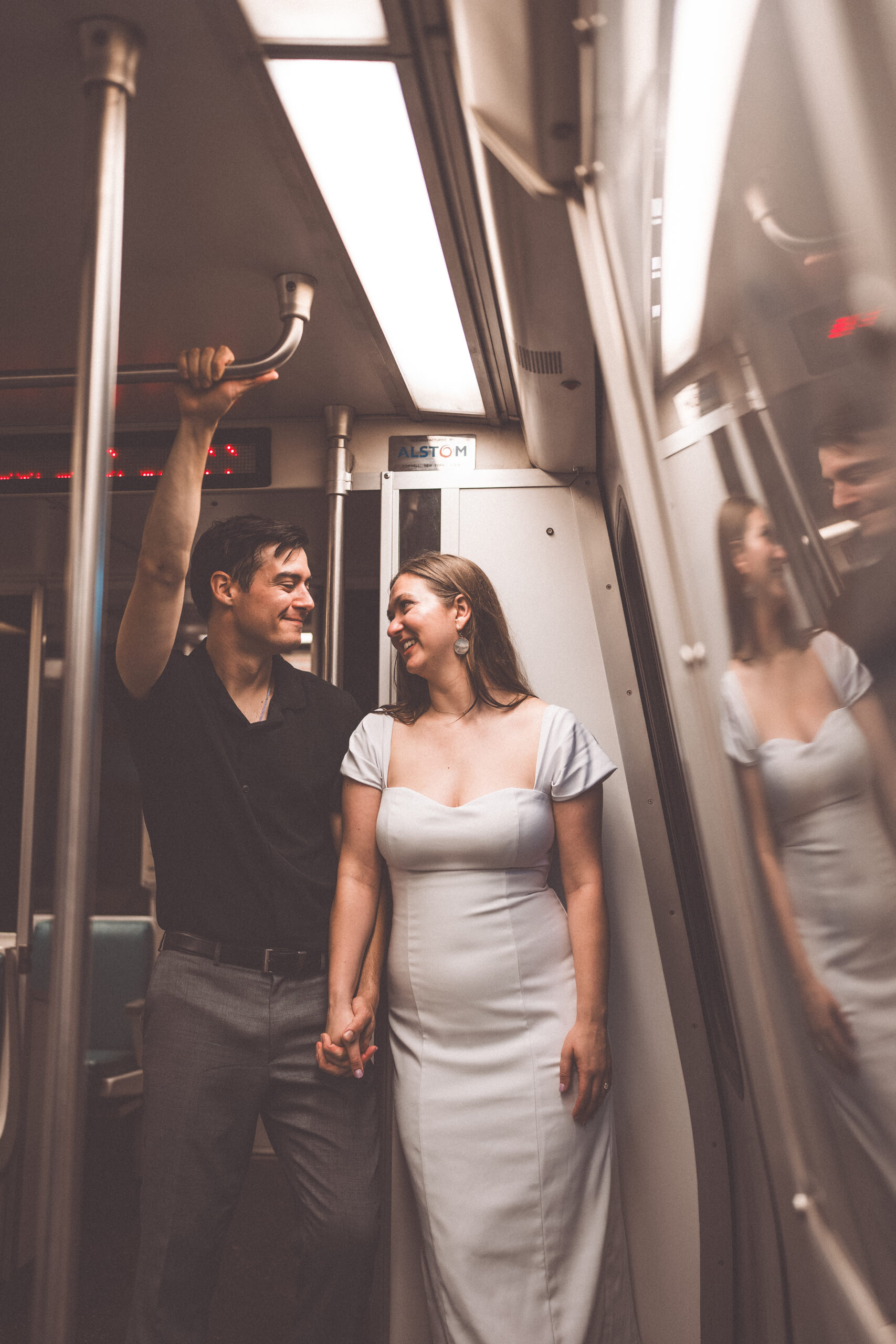 Romantic portrait of an engaged couple holding hands inside a Washington Metro train car
