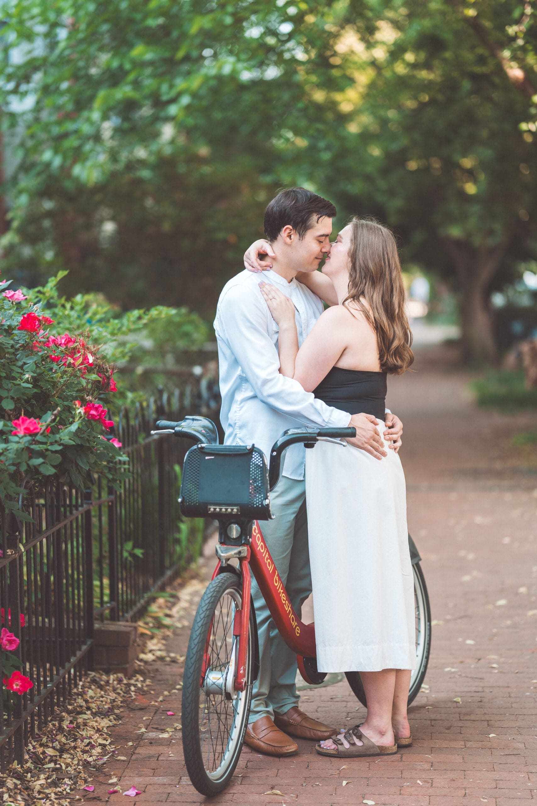 Romantic portrait of a couple embracing beside a Capital Bikeshare bike on a quiet neighborhood sidewalk during Washington DC engagement photos