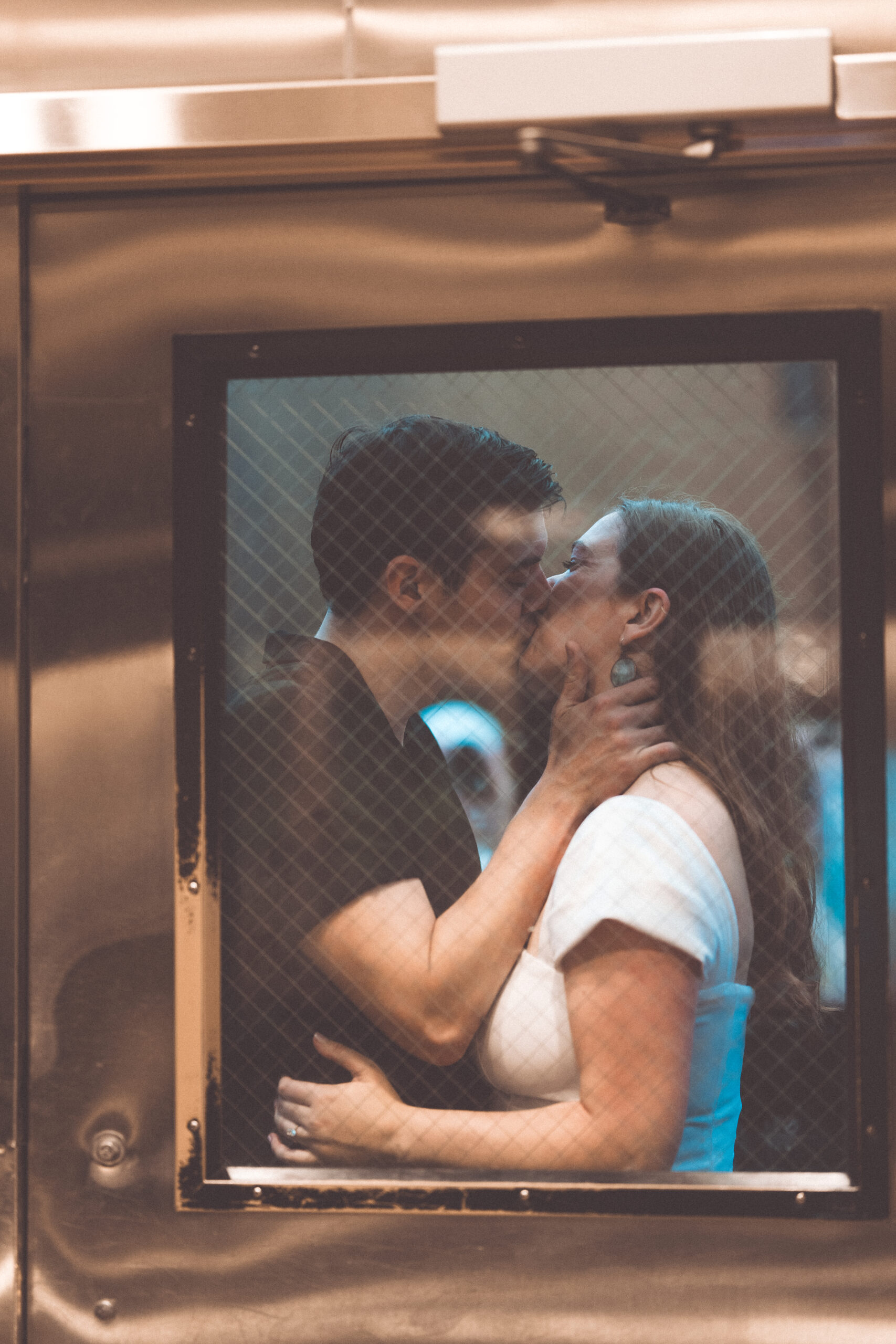 Intimate candid of a couple kissing through the window of a Washington Metro train during Washington DC engagement photos