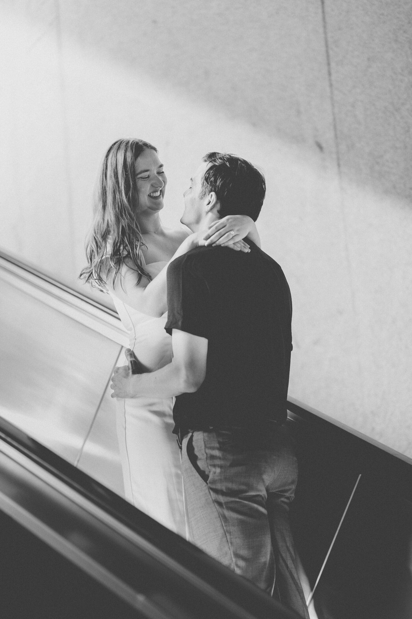 Black and white candid of a couple laughing together on a metro escalator during their Washington DC engagement photos