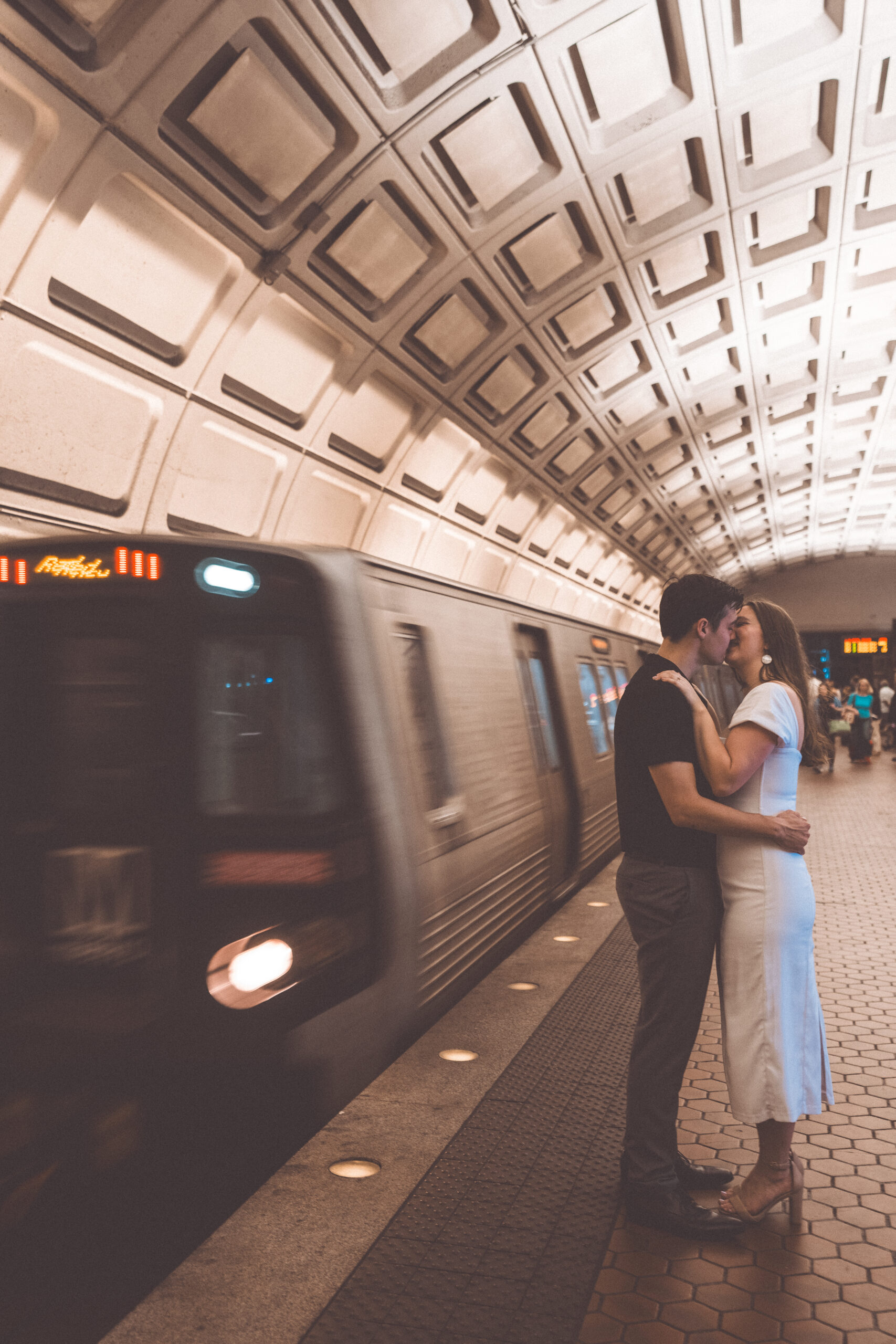 Couple kissing on a Washington Metro platform as a train passes by during romantic Washington DC engagement photos