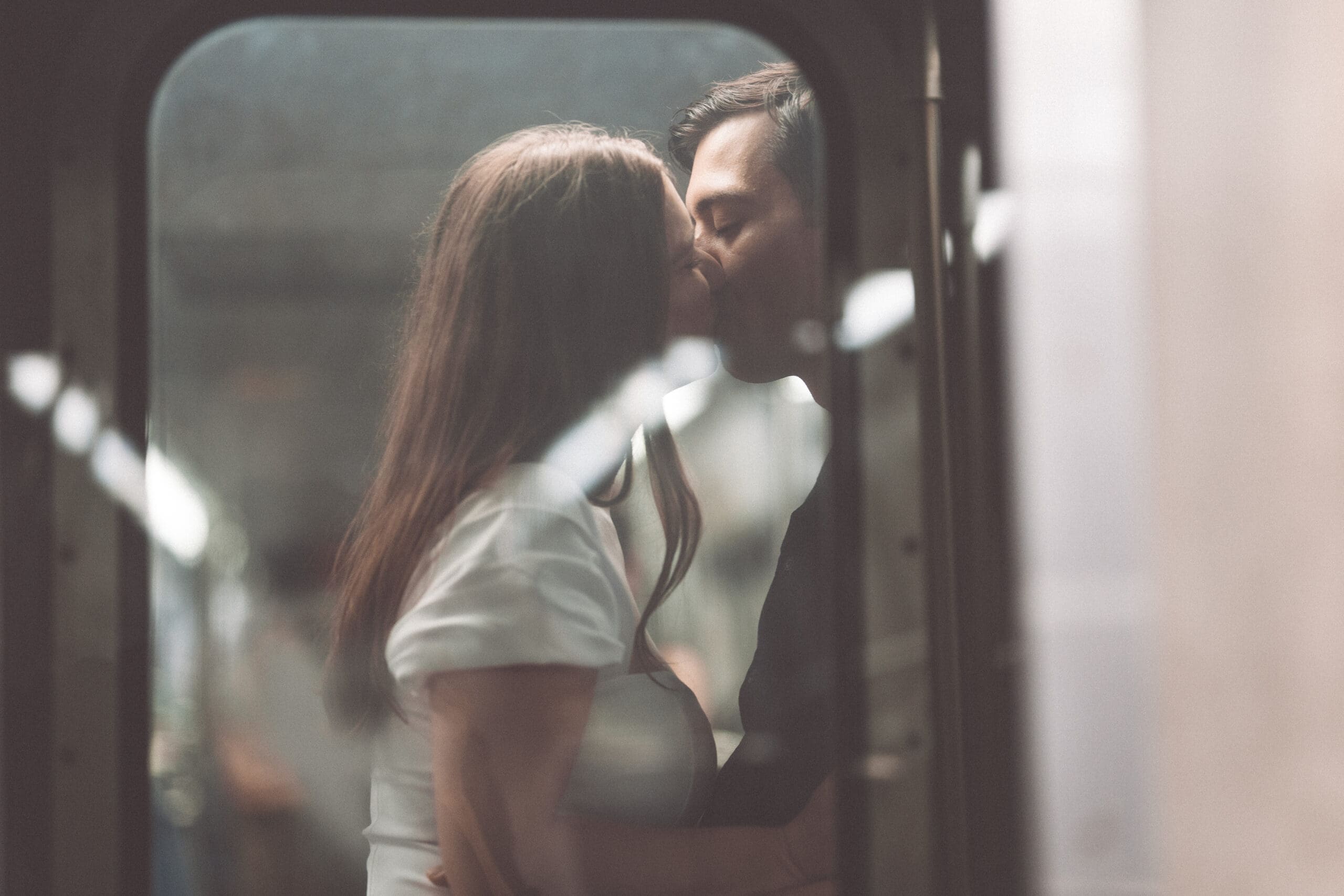 Soft, intimate portrait of an engaged couple kissing inside the metro with dreamy blurred framing during Washington DC engagement photos