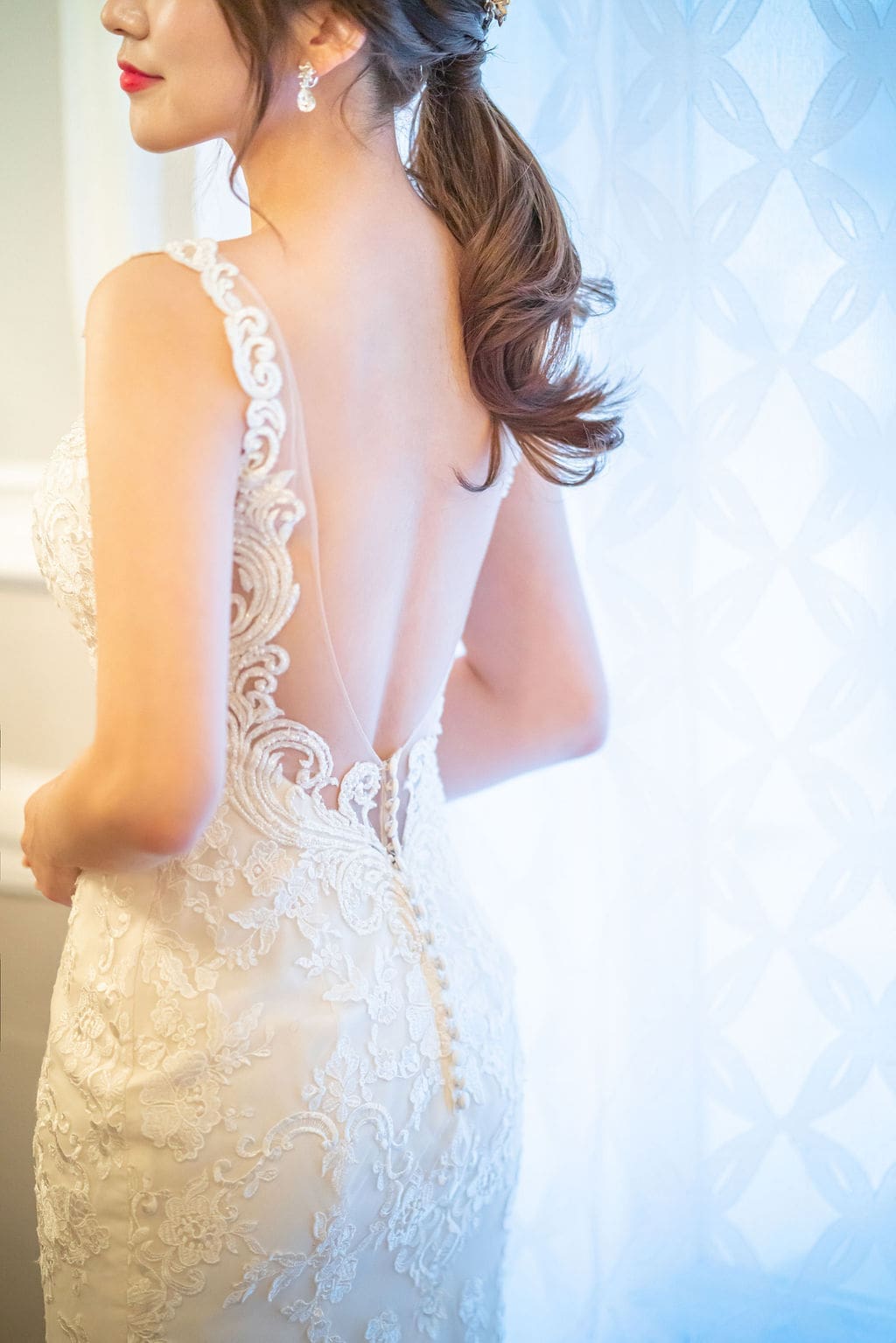 Detailed view of a lace wedding gown featuring an open-back design and intricate embroidery.