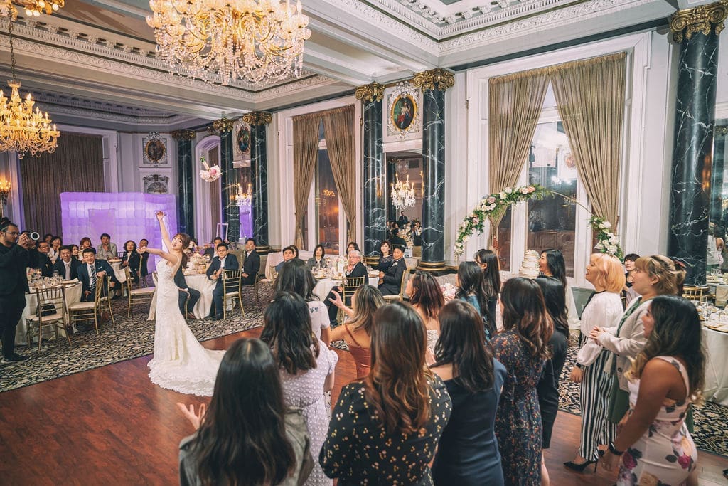 Bride tossing her bouquet to a crowd of guests during the wedding reception at The Belvedere Maryland.