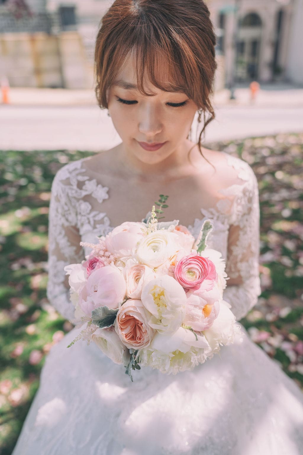 Close-up bridal portrait holding a pastel wedding bouquet beneath cherry blossoms at The Belvedere Maryland.