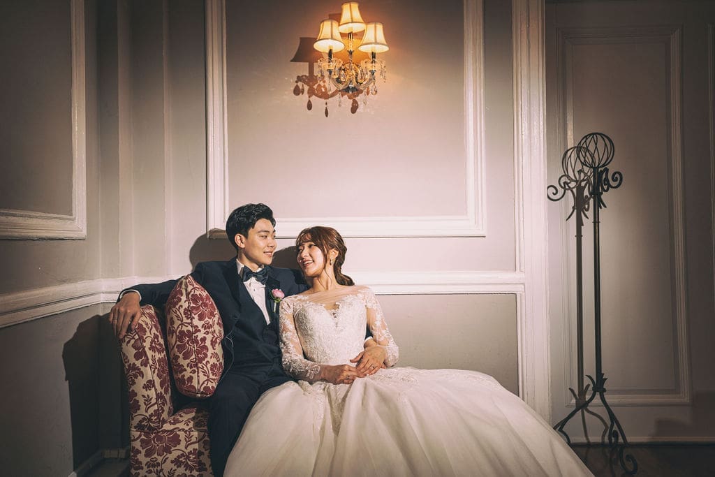 Newlywed couple sharing a quiet moment together on a vintage settee inside a historic Baltimore wedding venue.