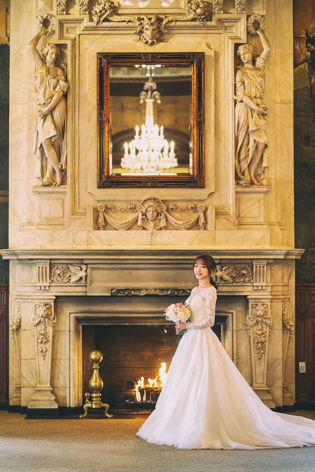 Bride standing in front of the ornate fireplace and chandelier inside a historic Baltimore wedding venue.