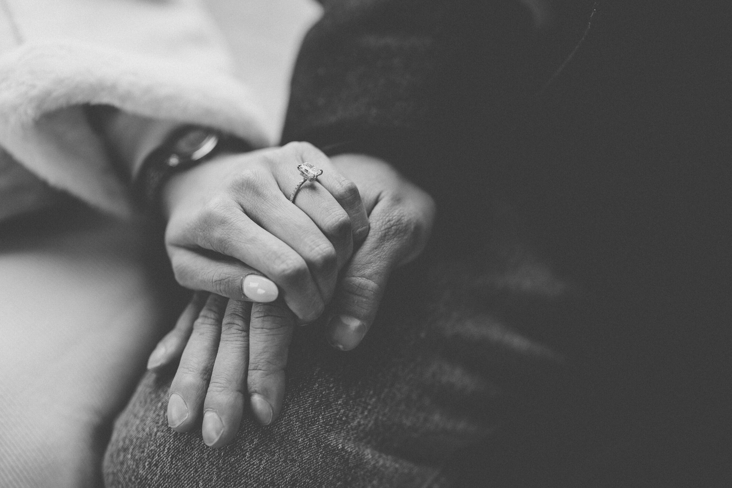 Black-and-white close-up of an engagement ring resting on intertwined hands after a Washington DC proposal.
