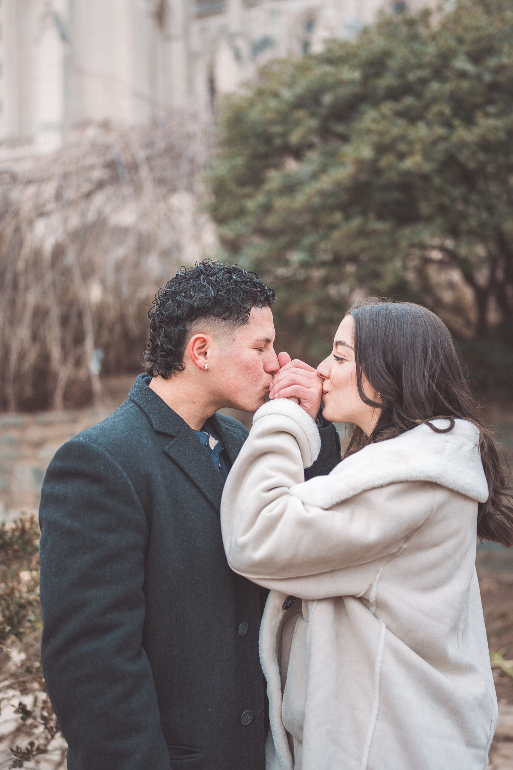 Couple sharing kissing each others hands during their engagement session at Washington National Cathedral.