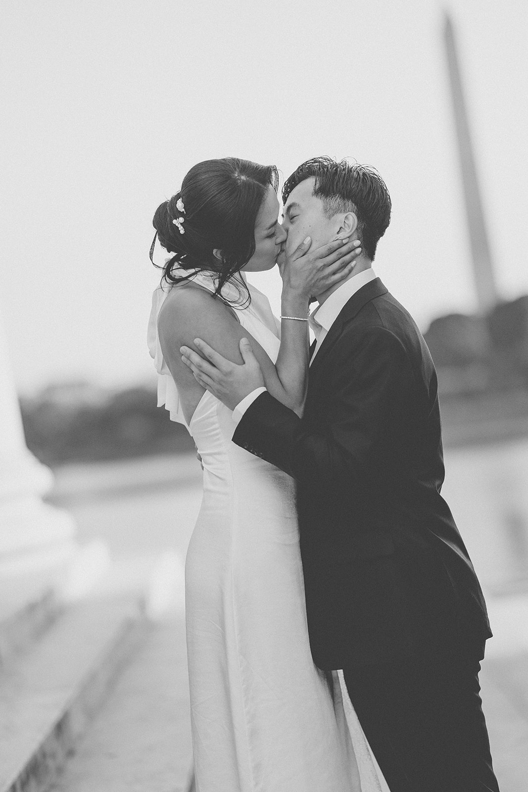 Black and white portrait of the couple sharing a kiss by the Tidal Basin.