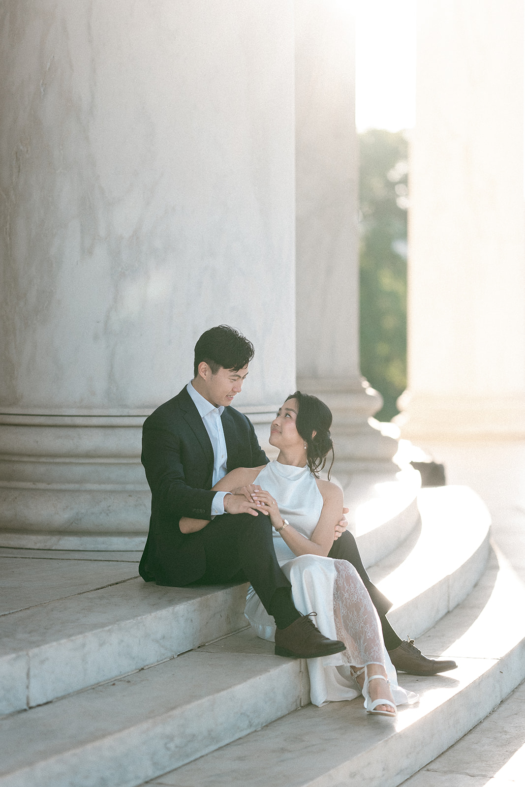 Couple sitting together on the Jefferson Memorial steps in soft golden light during a Washington DC engagement session.