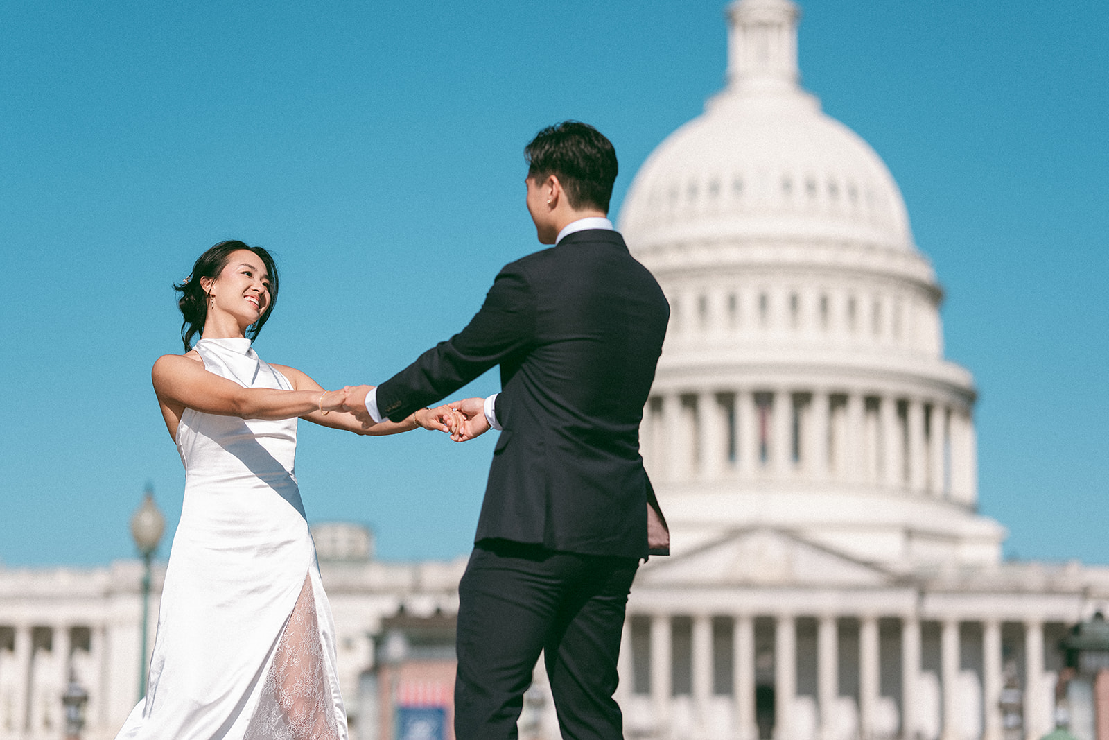 Couple holding hands with the U.S. Capitol in the background during a Washington DC engagement session.