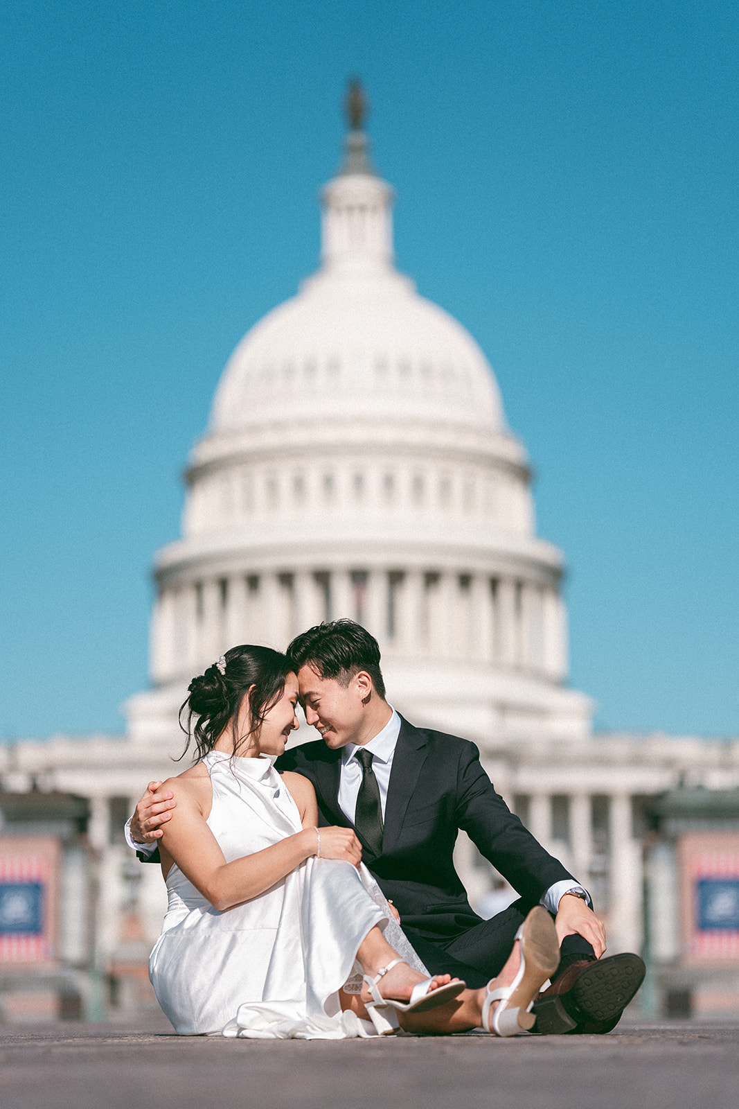 Couple sitting together in front of the U.S. Capitol during a Washington DC engagement session.