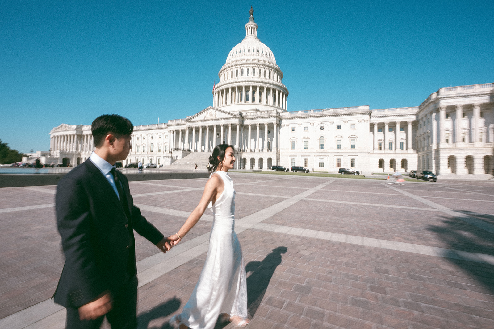 Couple walking hand in hand in front of the U.S. Capitol during a Washington DC engagement session.