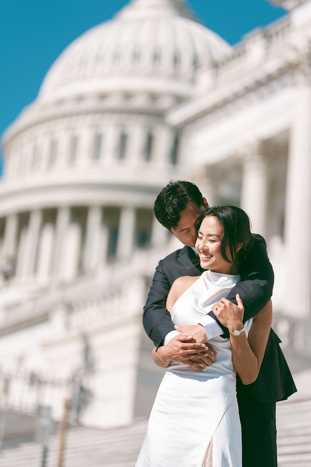 Groom hugging his fiancée in front of the U.S. Capitol during a Washington DC engagement session.