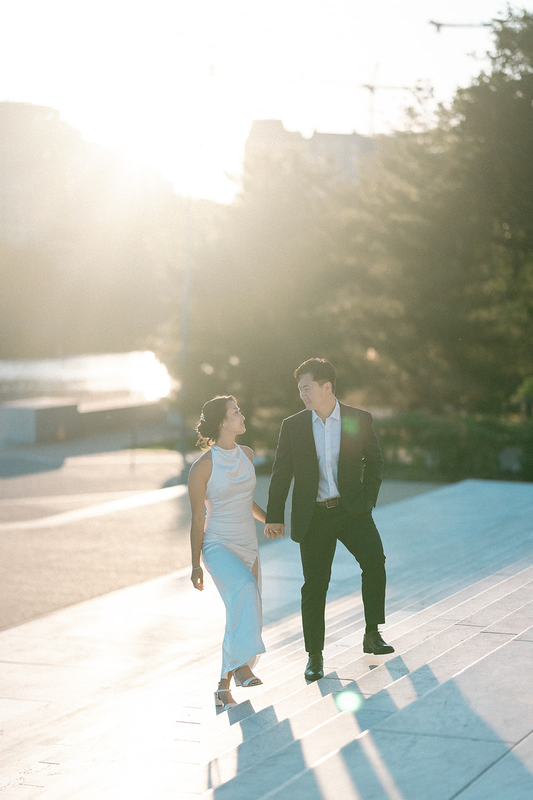 Couple holding hands and walking through golden evening light beside the Tidal Basin.
