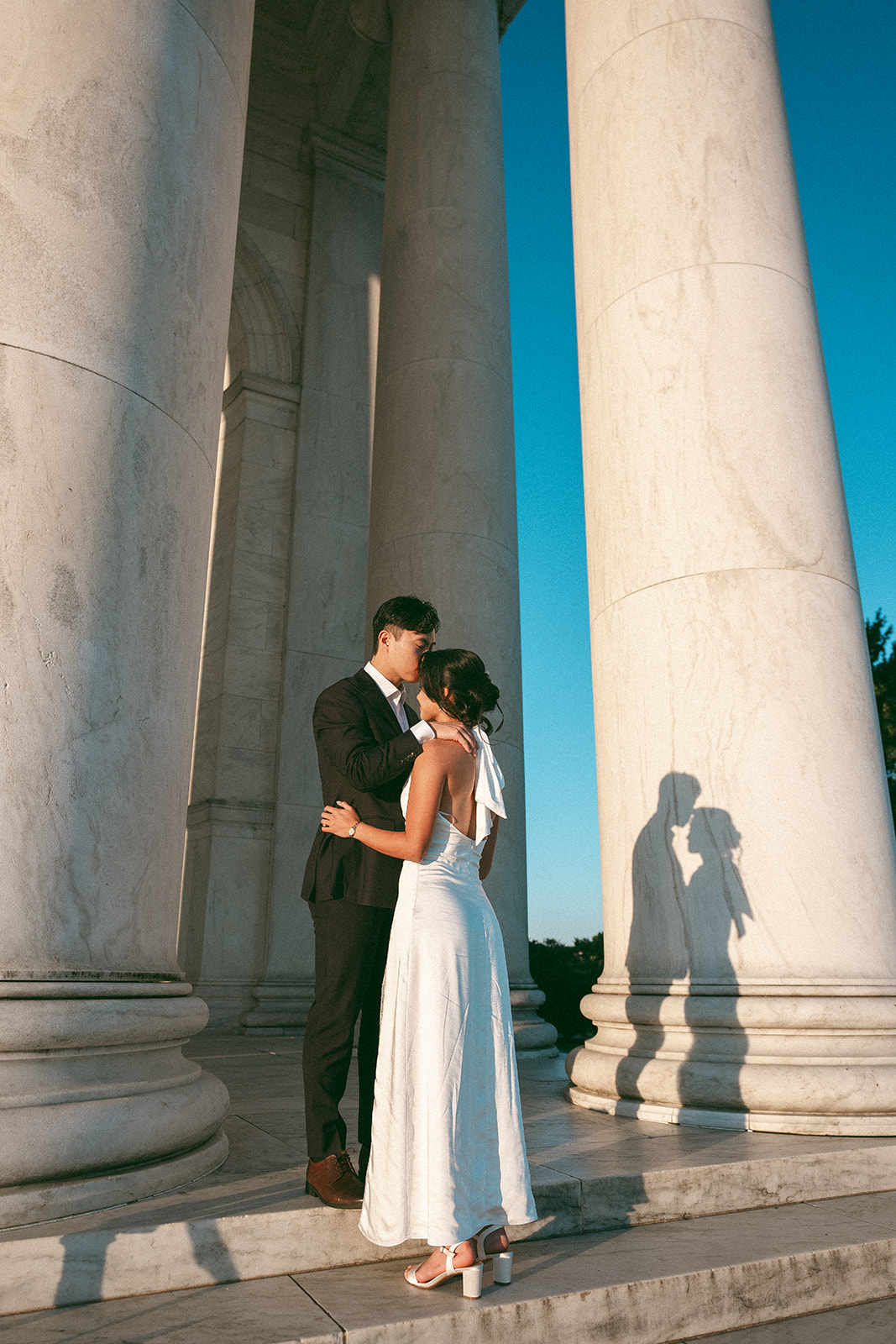 Couple kissing between the Jefferson Memorial columns during a Washington DC engagement session.
