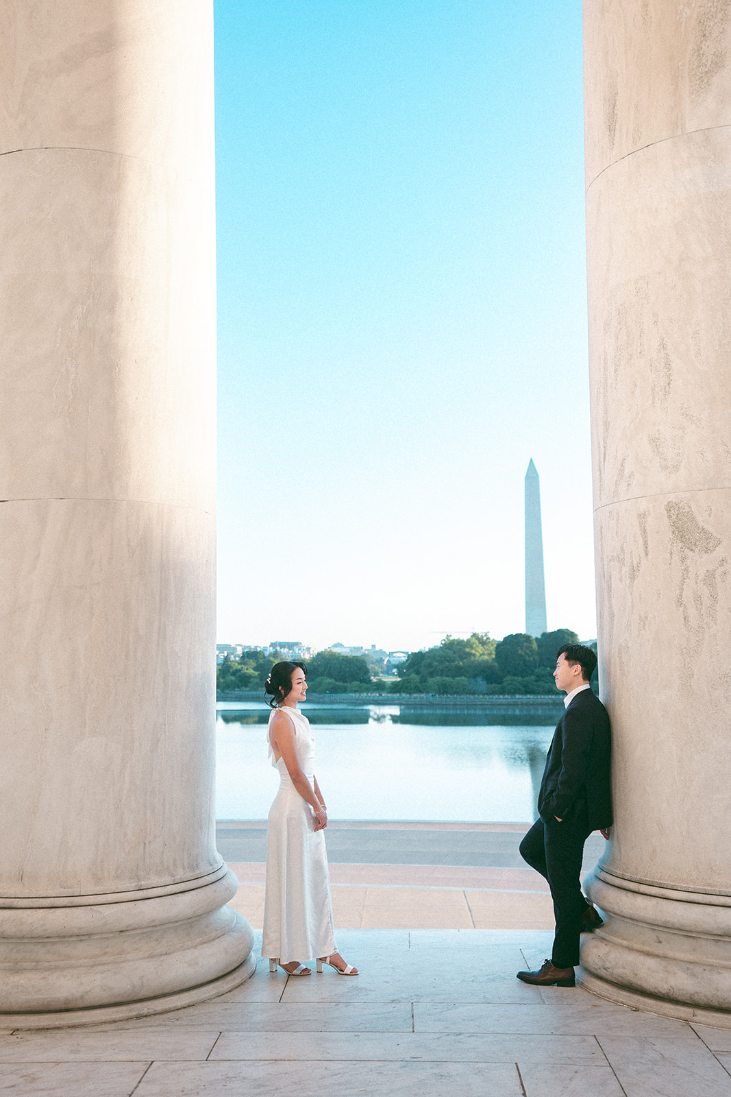 Couple standing between the Jefferson Memorial columns with the Washington Monument in the background.