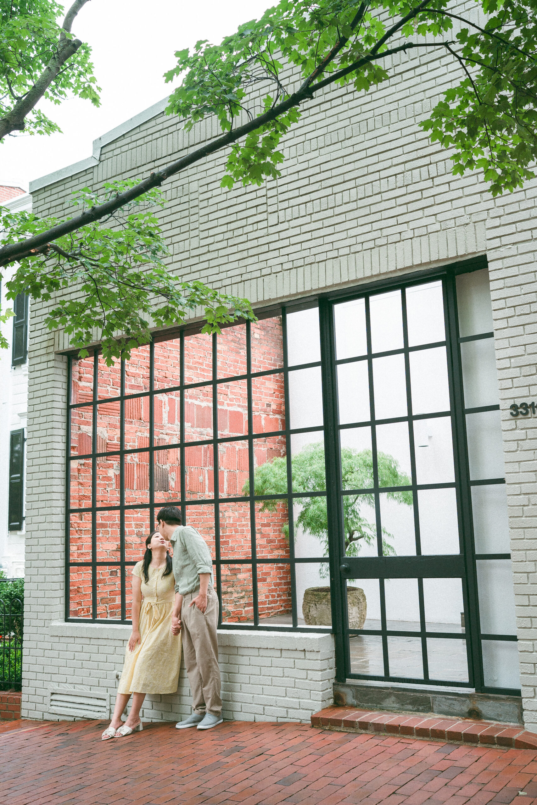 Couple sharing a quiet moment outside a modern brick building after the rain.