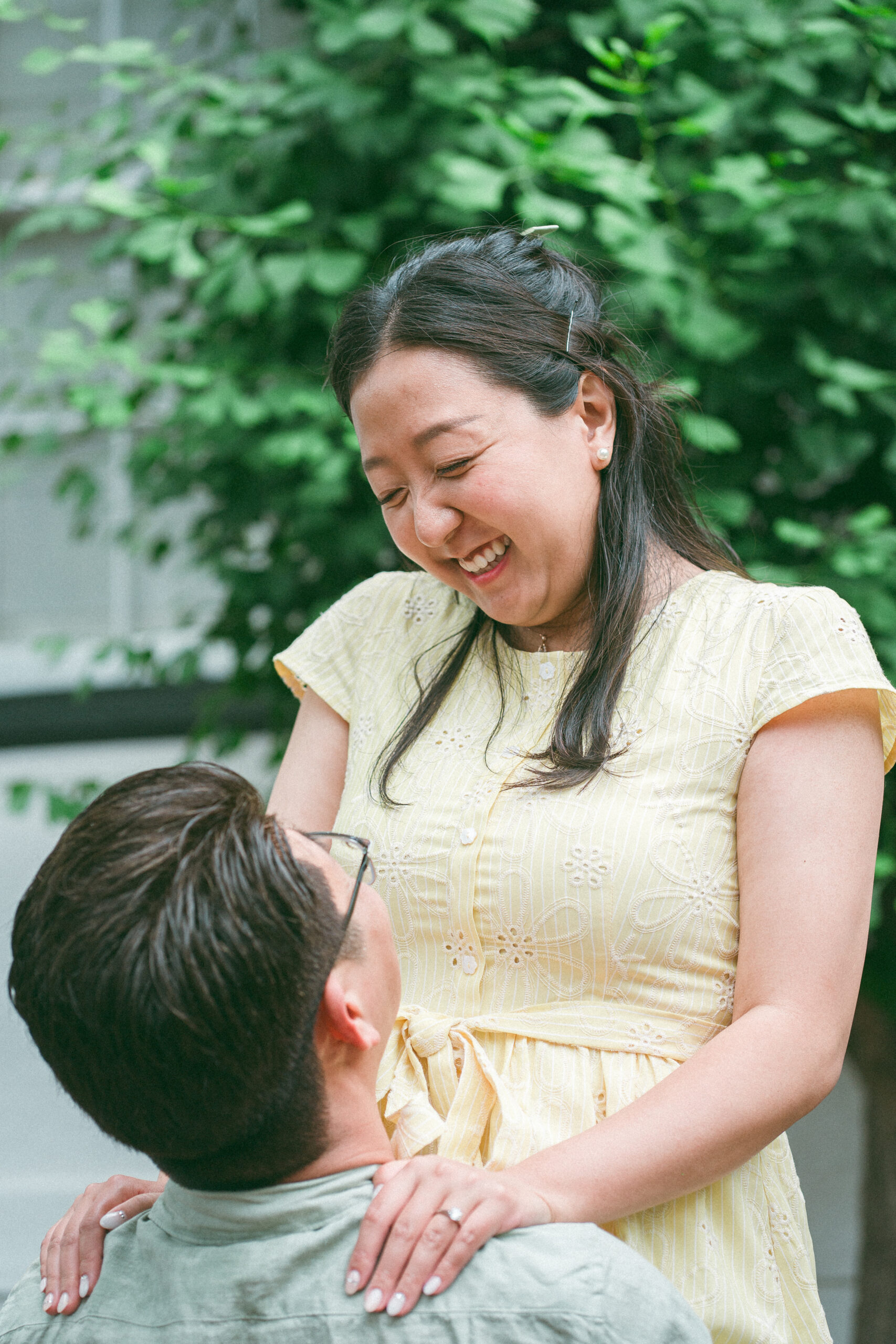 Bride-to-be smiling down at her partner as he holds her during a rainy engagement photos session.