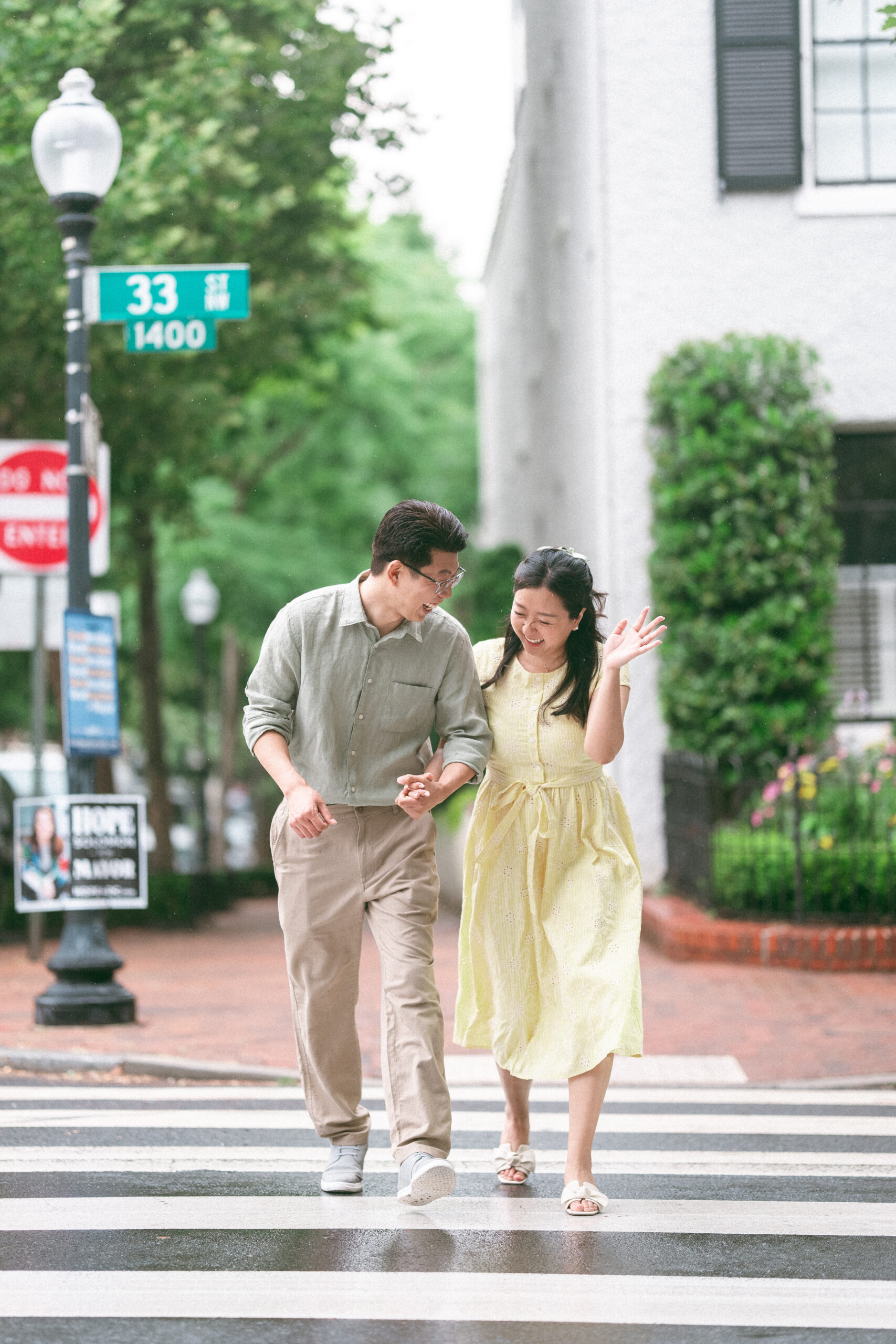 Couple laughing together while crossing a rain-soaked street hand in hand.