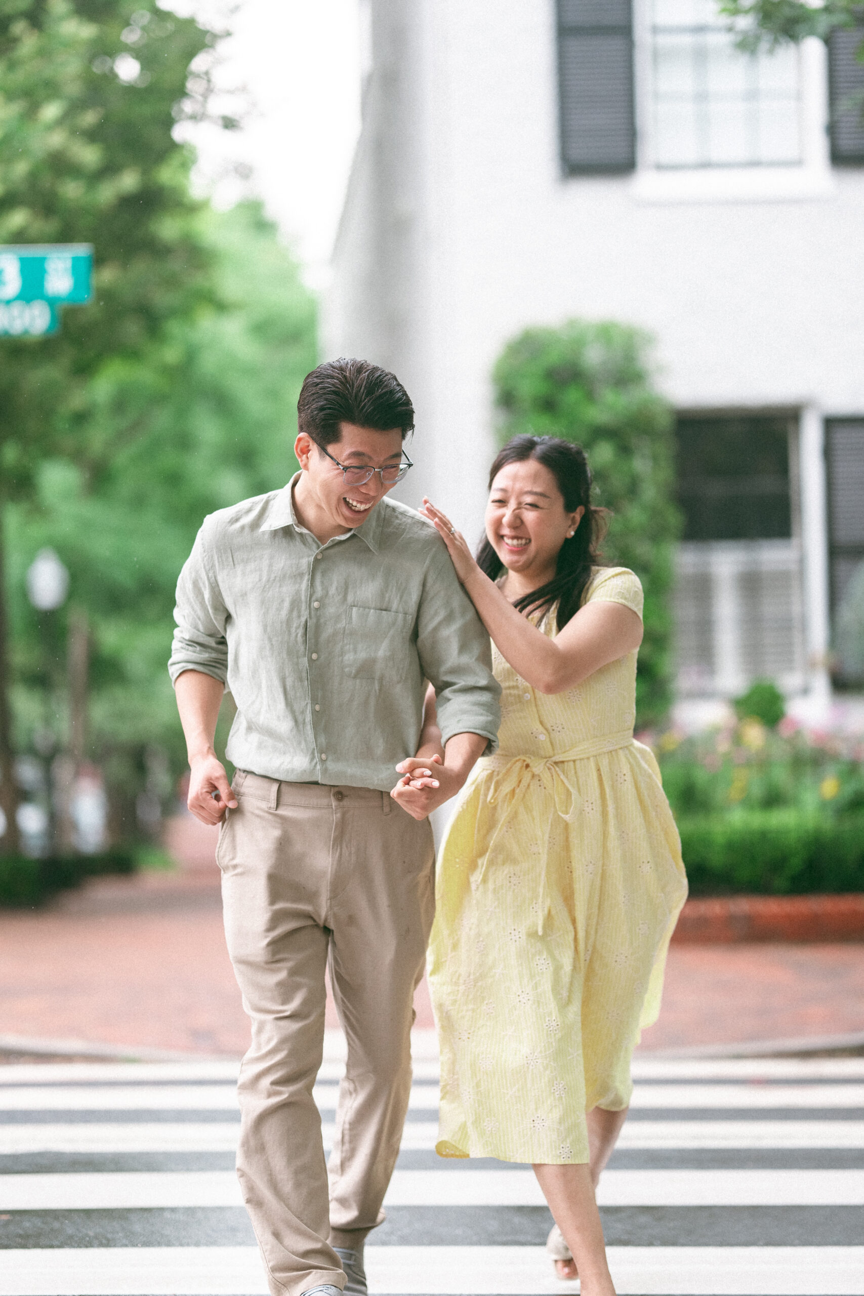 Couple laughing together while walking hand in hand across a crosswalk after the rain.