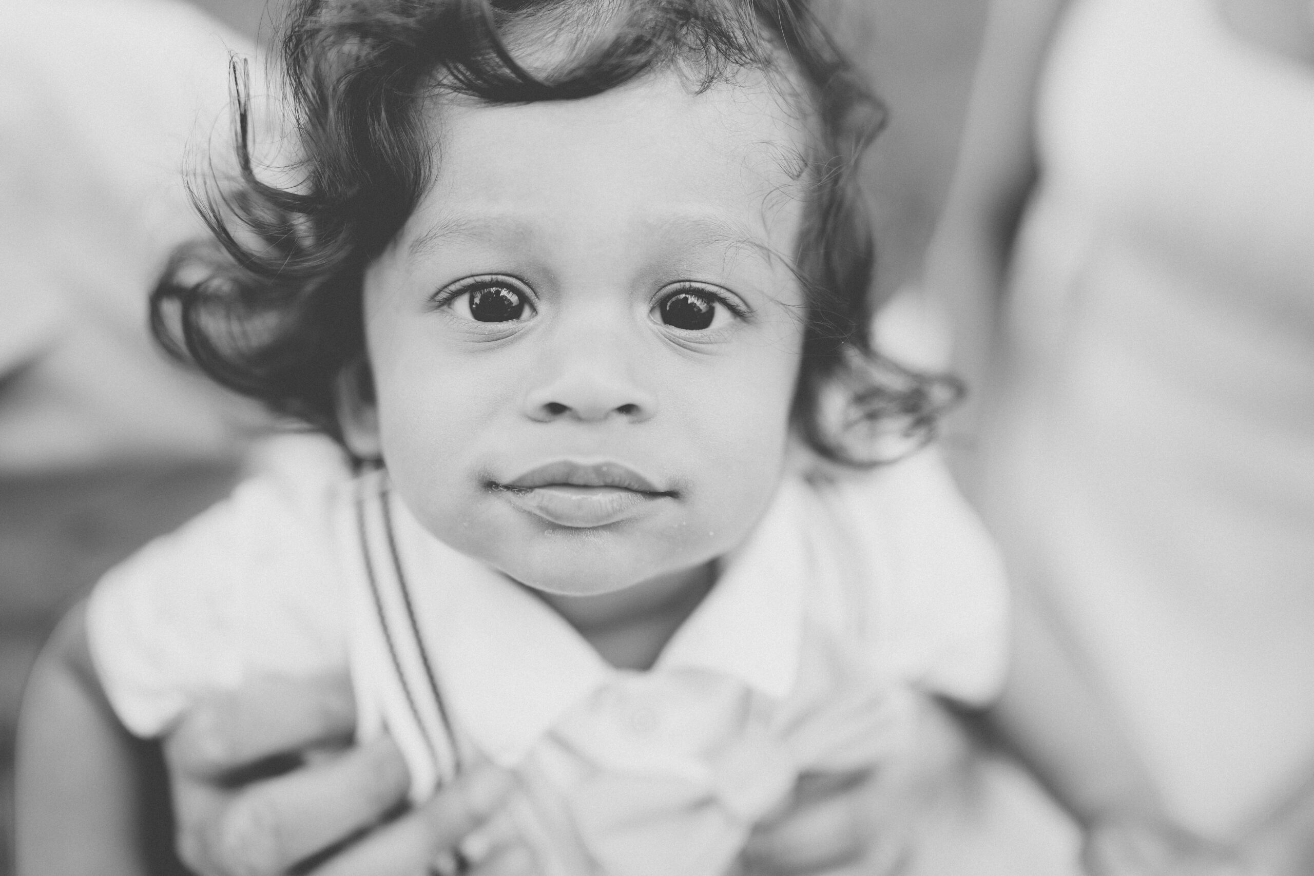 Black and white close-up portrait of a toddler looking directly into the camera.
