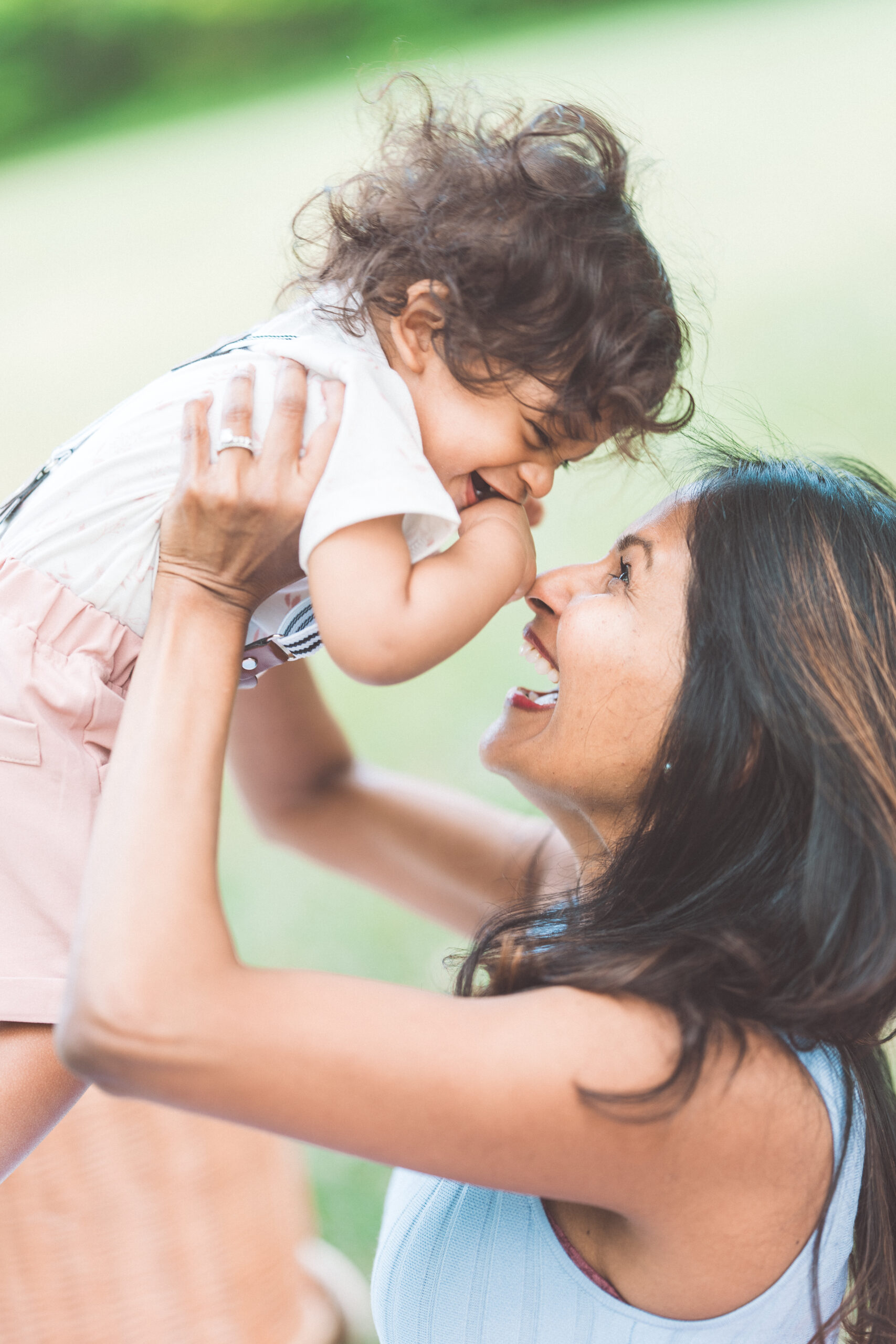 Mother lifting her toddler into the air during an outdoor family session.
