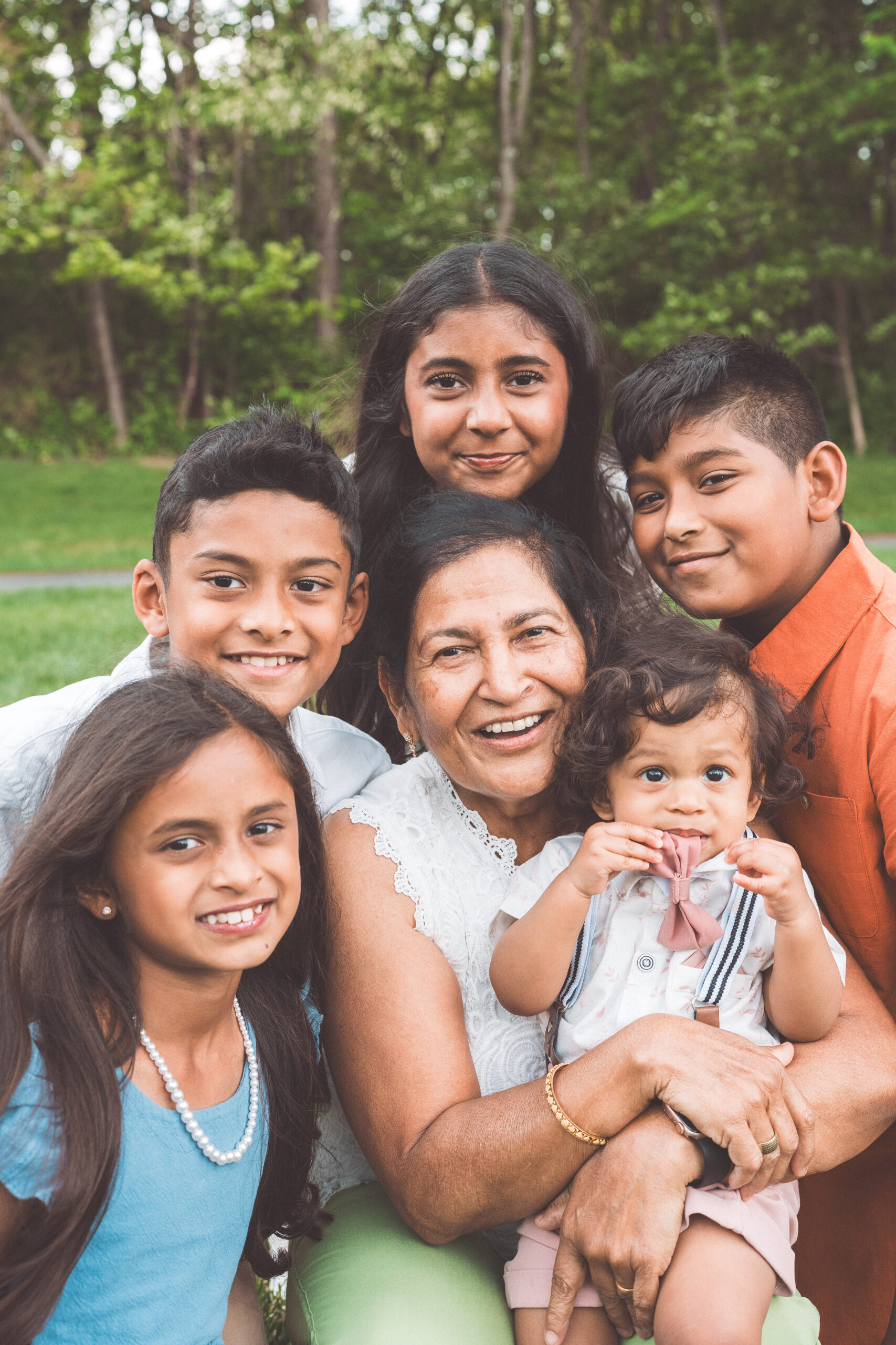 Grandmother surrounded by her grandchildren and great-grandchild during a joyful family portrait.