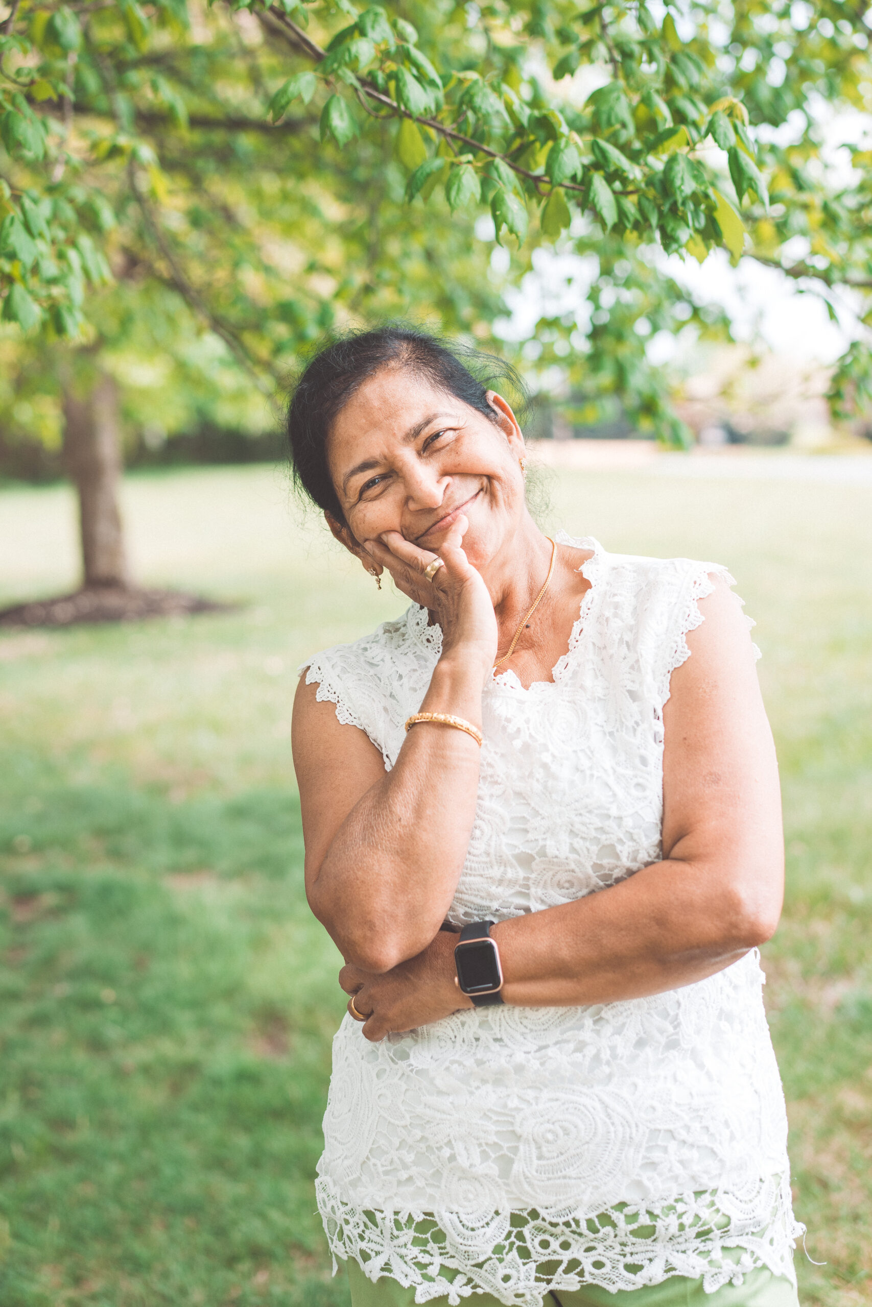 Grandmother smiling beneath a tree in a relaxed outdoor portrait.