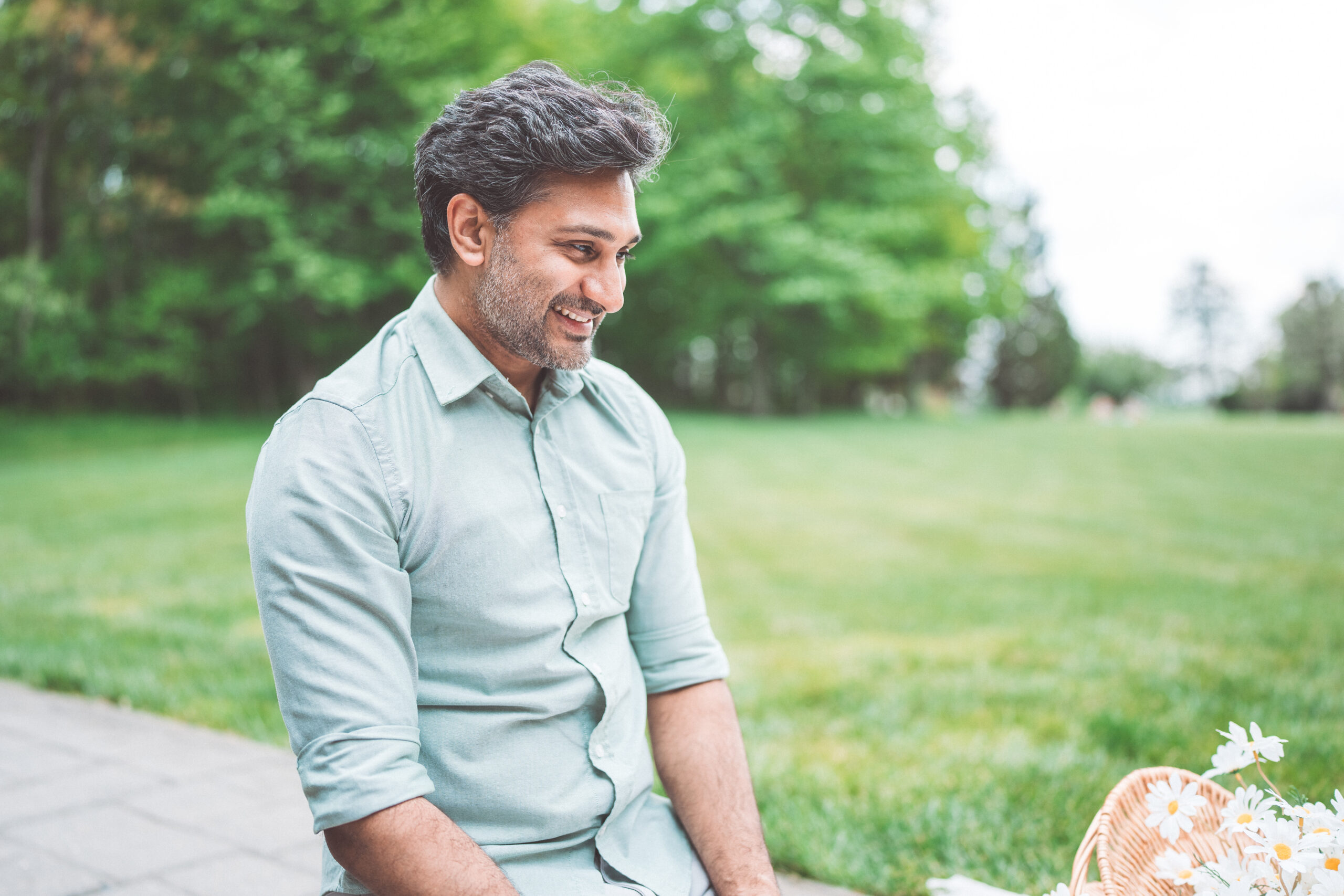 Dad smiling as he watches his family during a relaxed Maryland family photoshoot in the park.