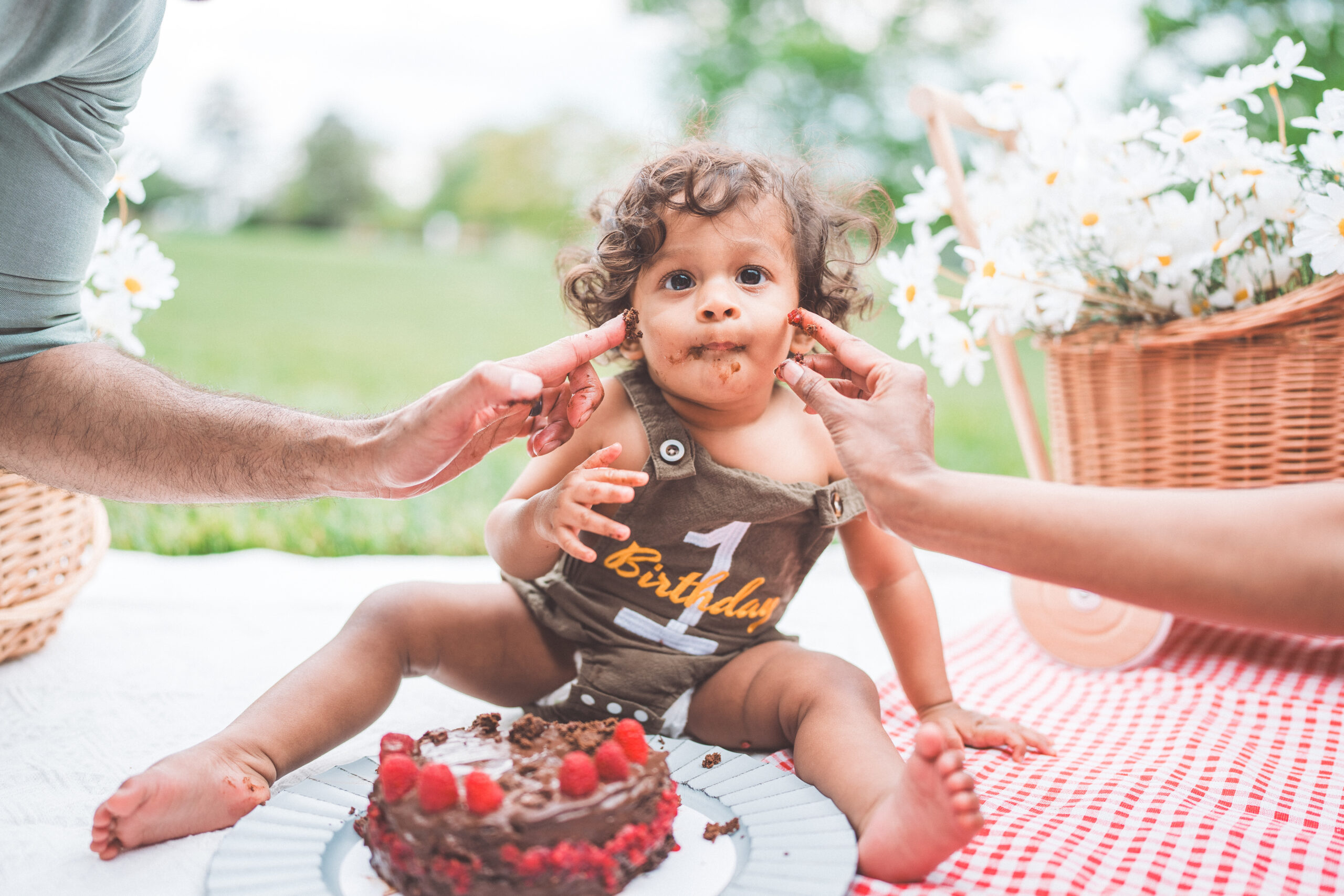 One-year-old with chocolate cake on their face during a fun first birthday cake smash.
