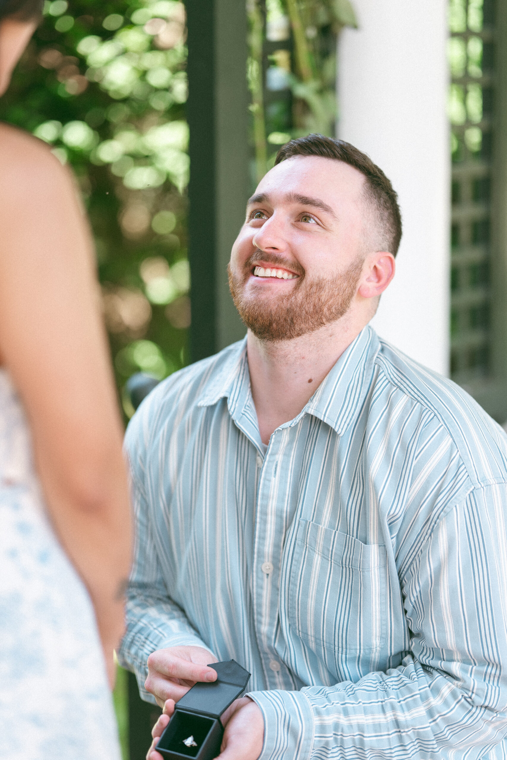 Groom-to-be smiling while proposing with the engagement ring.
