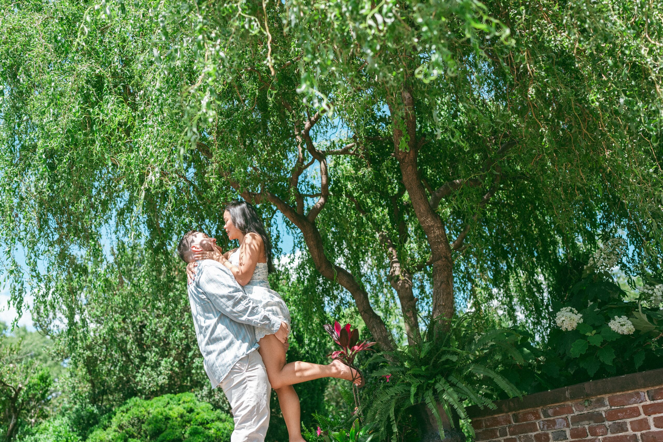 Couple embracing beneath lush trees after their Northern Virginia proposal.