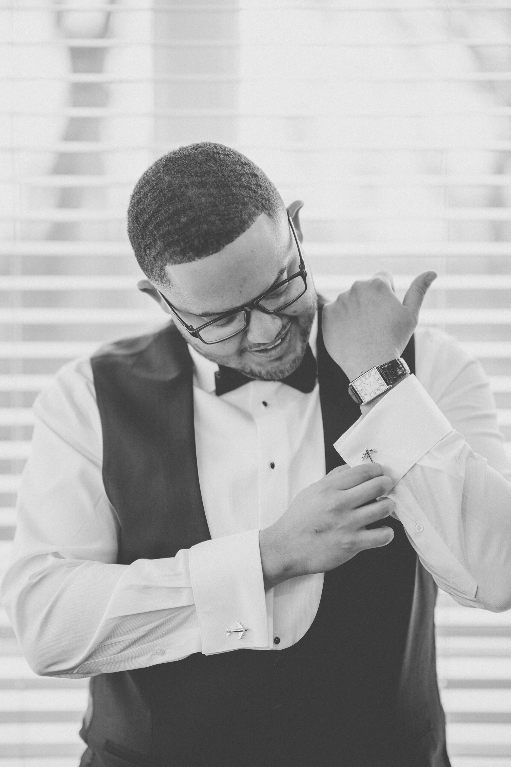 Black-and-white portrait of the groom adjusting his cufflinks and watch while getting ready for his Cameron Estate Inn wedding.