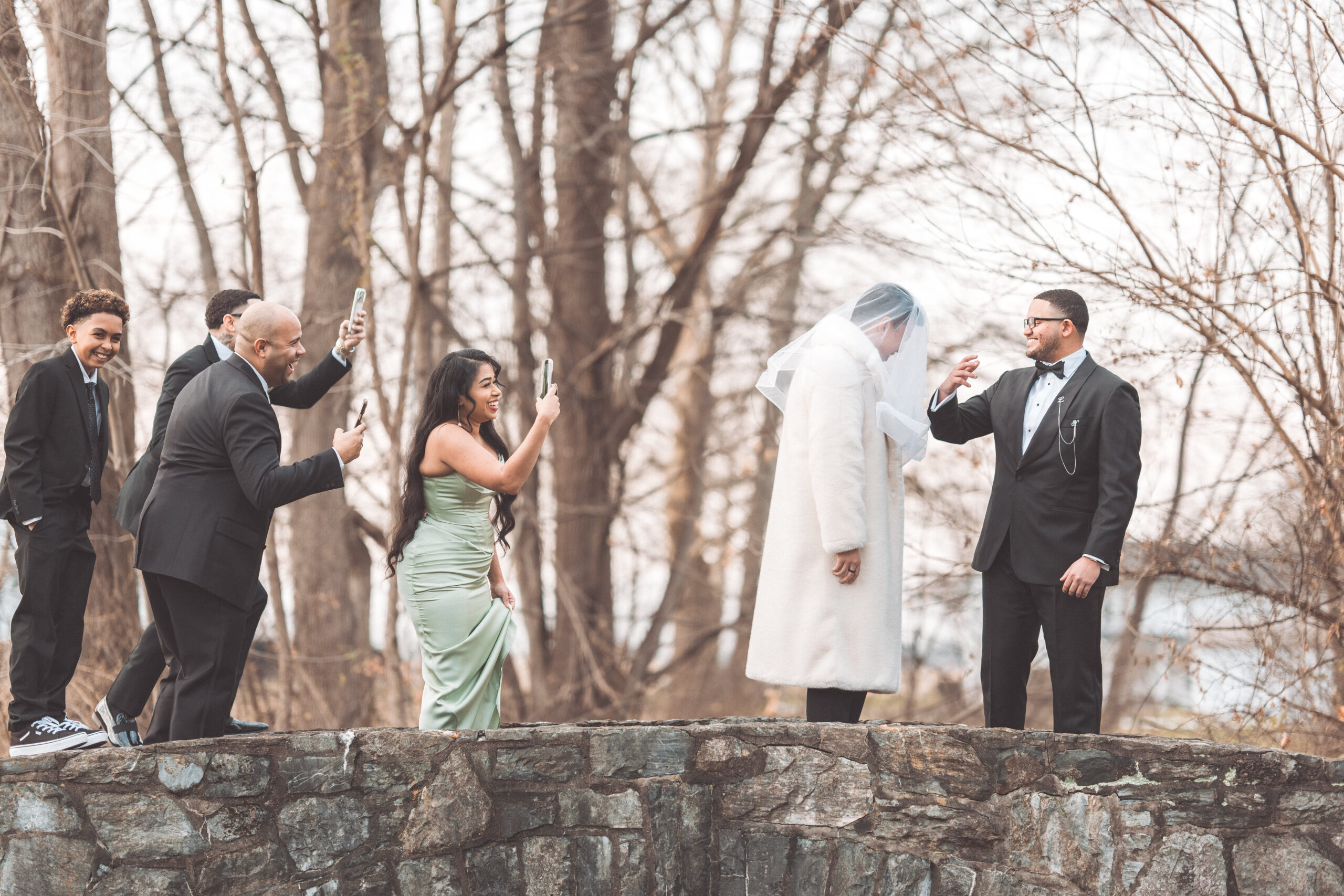 Groom laughing as friends playfully cover another man's face with a veil during wedding portraits at Cameron Estate Inn.