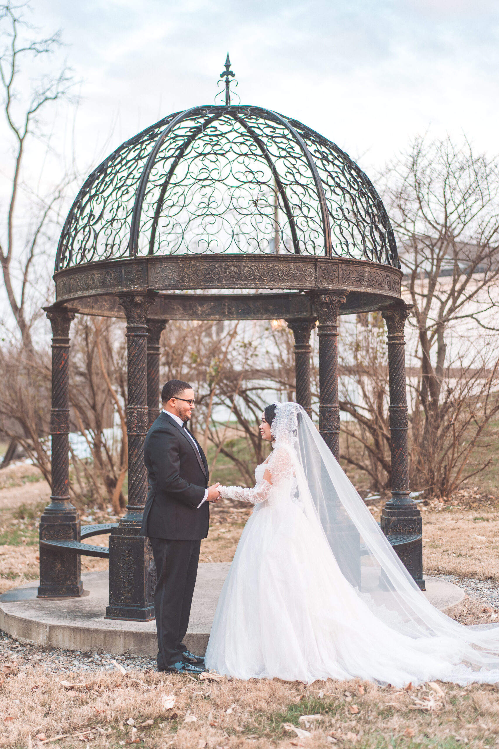Bride and groom holding hands beneath the ornate gazebo at Cameron Estate Inn.