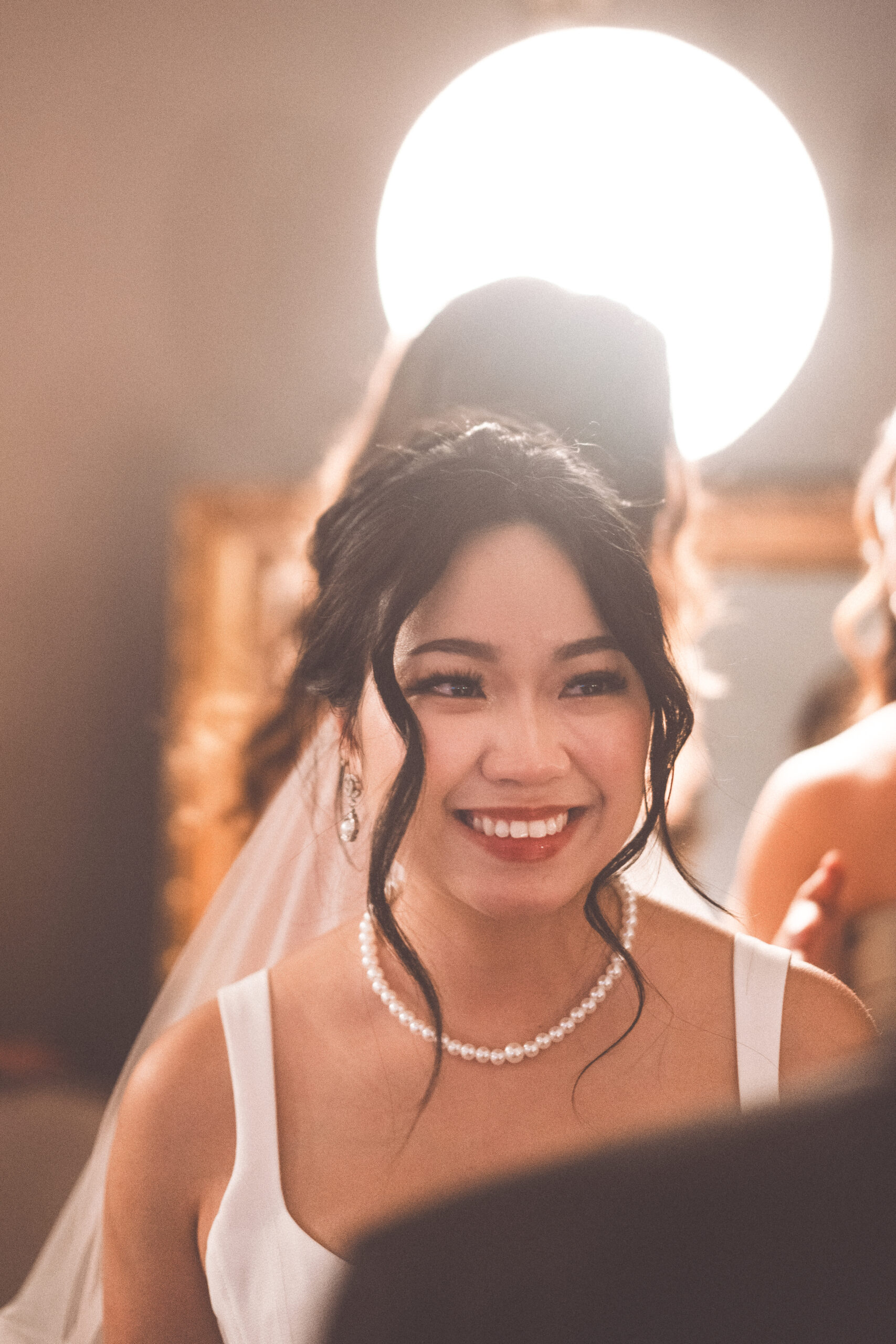 Close-up portrait of the smiling bride wearing pearl jewelry and an elegant updo at Cameron Estate Inn.