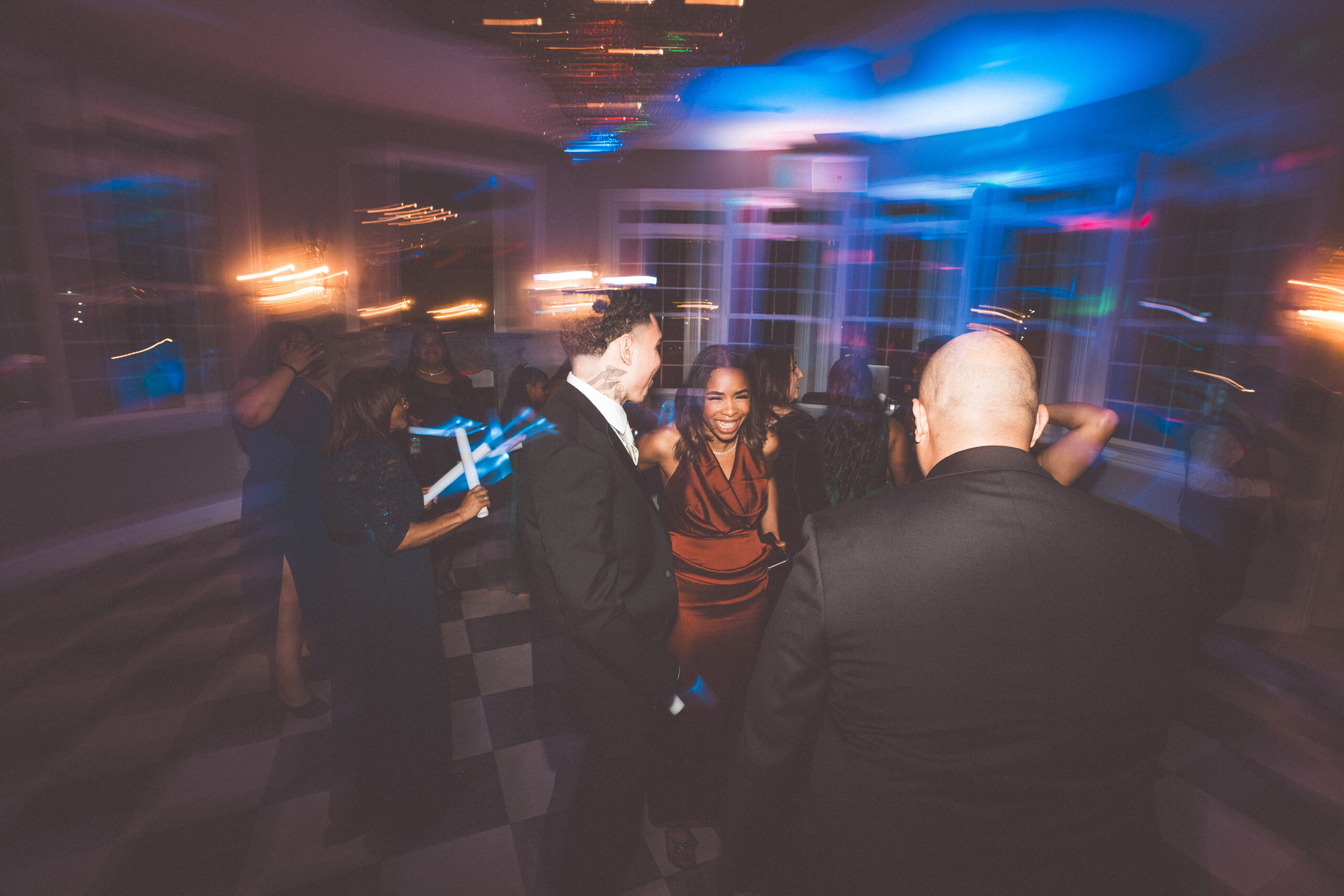 Wedding guests dancing under colorful reception lights during an energetic evening celebration.