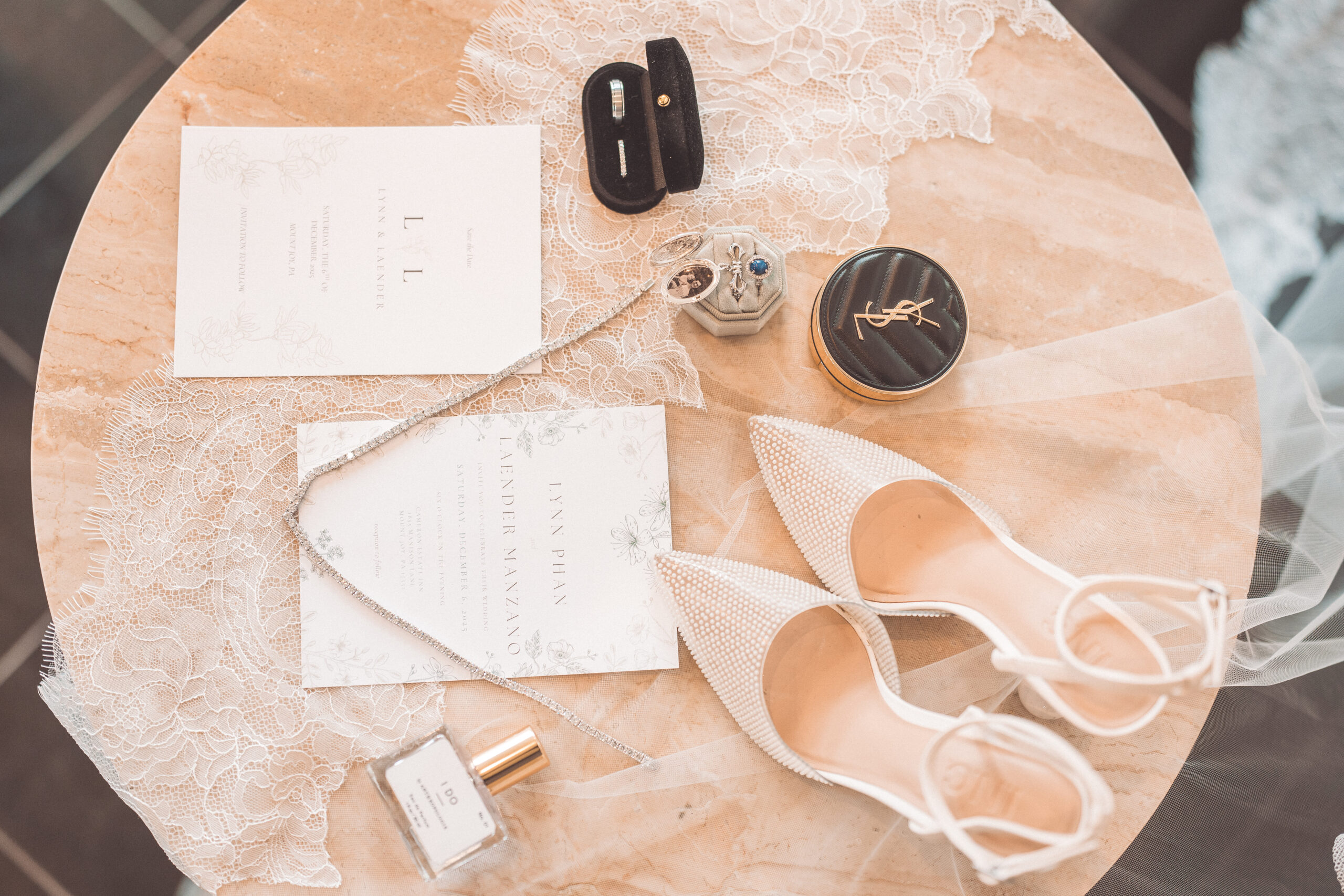 Wedding flat lay with invitations, rings, jewelry, lace, makeup, and pearl bridal shoes at Cameron Estate Inn.