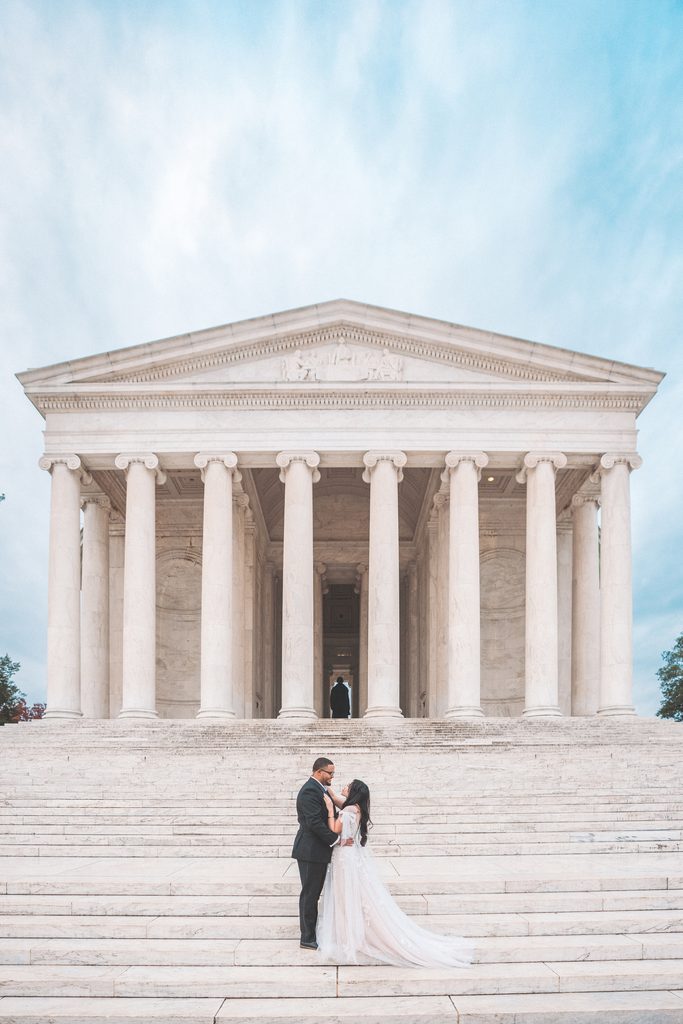 Couple walking hand in hand beneath the marble columns during their Jefferson Memorial engagement photos in Washington DC.