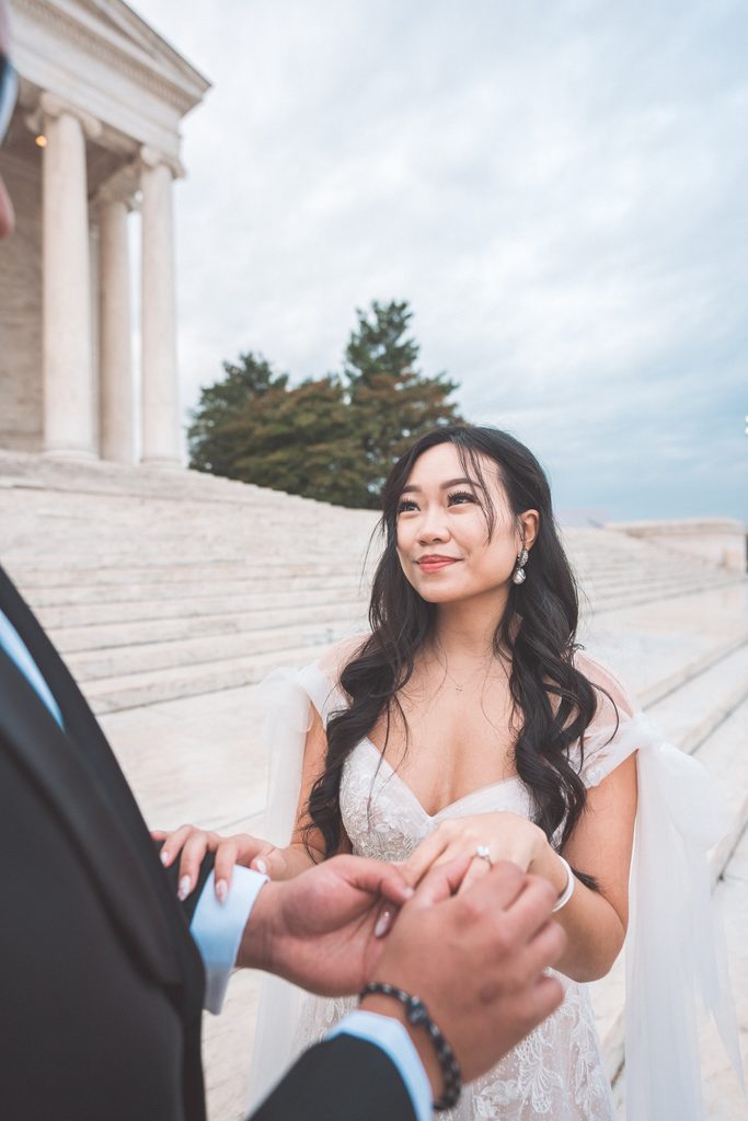 Bride-to-be smiling at her fiancé while showing her new engagement ring on the Jefferson Memorial steps.