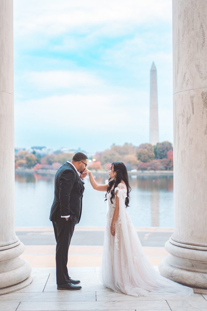 Couple holding hands beside the Tidal Basin with the Washington Monument in the background during their Jefferson Memorial engagement photos.