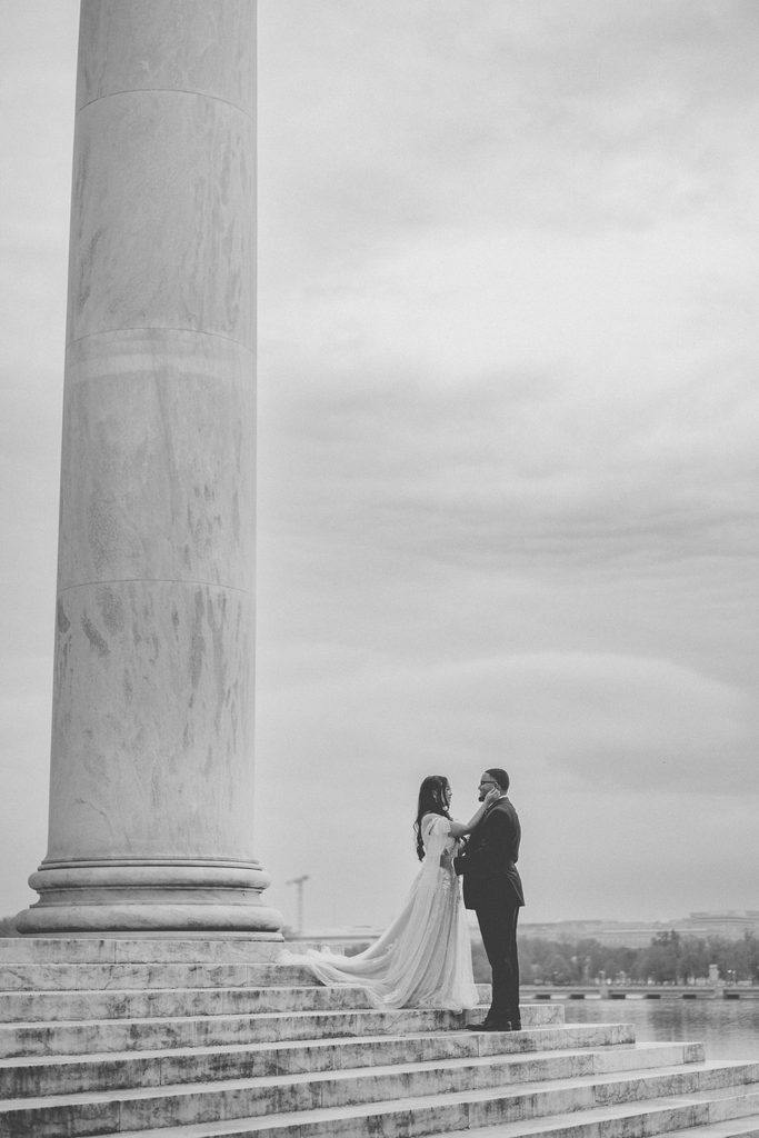 Engaged couple smiling and embracing together beneath the Jefferson Memorial’s classic marble architecture.